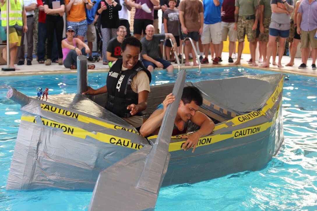 The Retired Pirates, Army Maj. Erin Reed and Rey Santos, work to move their massive boat known as the USS OuterLimits through the water at the Naval Support Activity Bahrain 240th Navy Birthday Cardboard Regatta Oct. 8.