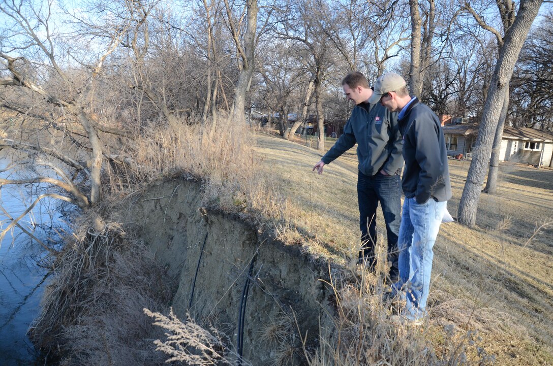 Derek Ingvalson, planning, left and Nathan Wallerstedt, project manangement, review erosion to the Souris Court Levee in Minot, N.D. The levee was damanged during floods in 2011.