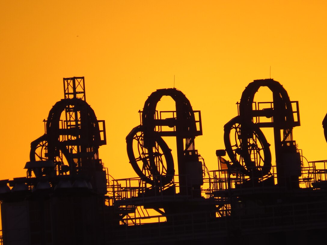 The sun rises behind the catamaran barge at the Olmsted Dam construction project on the lower Ohio River. Shown are the strand jacks atop the barge. Strand jacks are hydraulically operated lifting devices, capable of lifting extremely heavy loads. There are 12 strand jacks on the catamaran barge that can be rearranged depending on the item that is being lifted.              