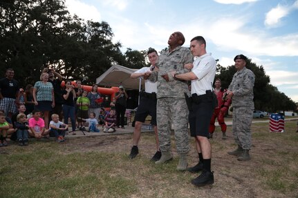 Tech. Sgt. Mark Fox (center), 902nd Security Forces Squadron NCO in charge of police services, demonstrates how security forces members can use a taser against criminals during National Night Out Oct. 6 at Joint Base San Antonio-Randolph. Each year on the second Tuesday of October, National Night Out takes place in communities across the nation to foster positive relationships between neighbors and law enforcement members.