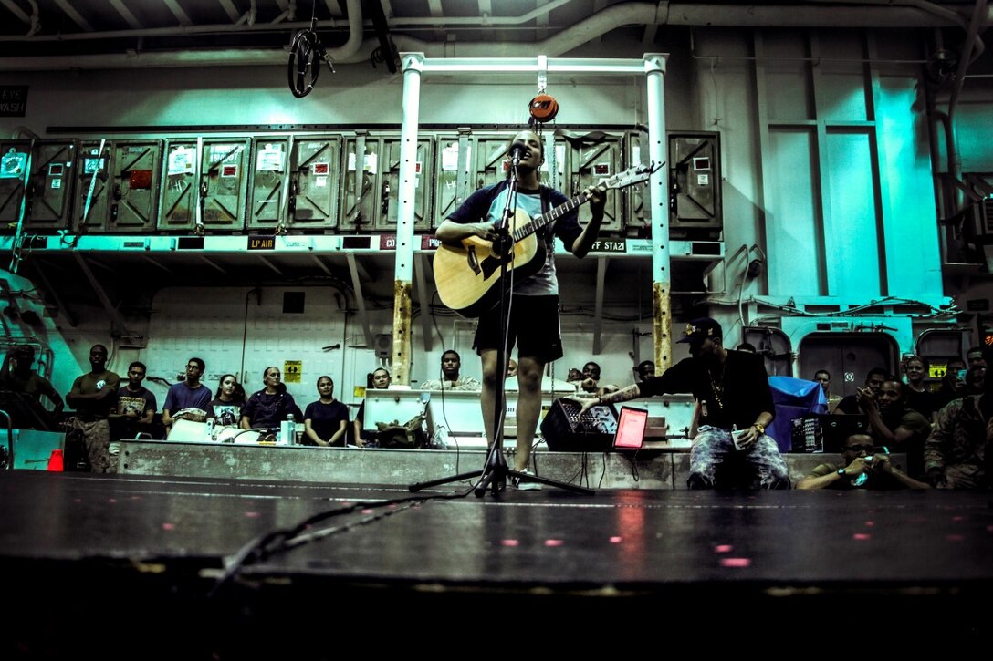 GULF OF ADEN (July 12, 2015) U.S. Marine Lance Cpl. Brianna Mikus sings and plays her guitar during a talent show in the hangar bay of the amphibious assault ship USS Essex (LHD 2). Mikus is a radio operator with Combat Logistics Battalion 15, 15th Marine Expeditionary Unit. The Essex finds time to enhance unit moral by highlighting Marines and Sailors with the 15th MEU and Essex Amphibious Ready Group’s talents during their deployment. The 15th MEU is embarked on the Essex ARG and deployed to maintain regional security in the U.S. 5th Fleet area of operations. (U.S. Marine Corps photo by Cpl. Elize McKelvey/Released)