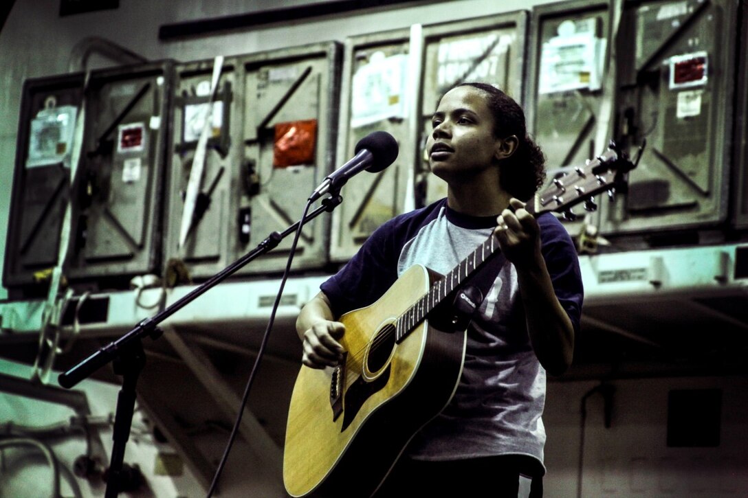 GULF OF ADEN (July 12, 2015) U.S. Marine Lance Cpl. Brianna Mikus sings and plays her guitar during a talent show in the hangar bay of the amphibious assault ship USS Essex (LHD 2). Mikus is a radio operator with Combat Logistics Battalion 15, 15th Marine Expeditionary Unit. The Essex finds time to enhance unit moral by highlighting Marines and Sailors with the 15th MEU and Essex Amphibious Ready Group’s talents during their deployment. The 15th MEU is embarked on the Essex ARG and deployed to maintain regional security in the U.S. 5th Fleet area of operations. (U.S. Marine Corps photo by Cpl. Elize McKelvey/Released)