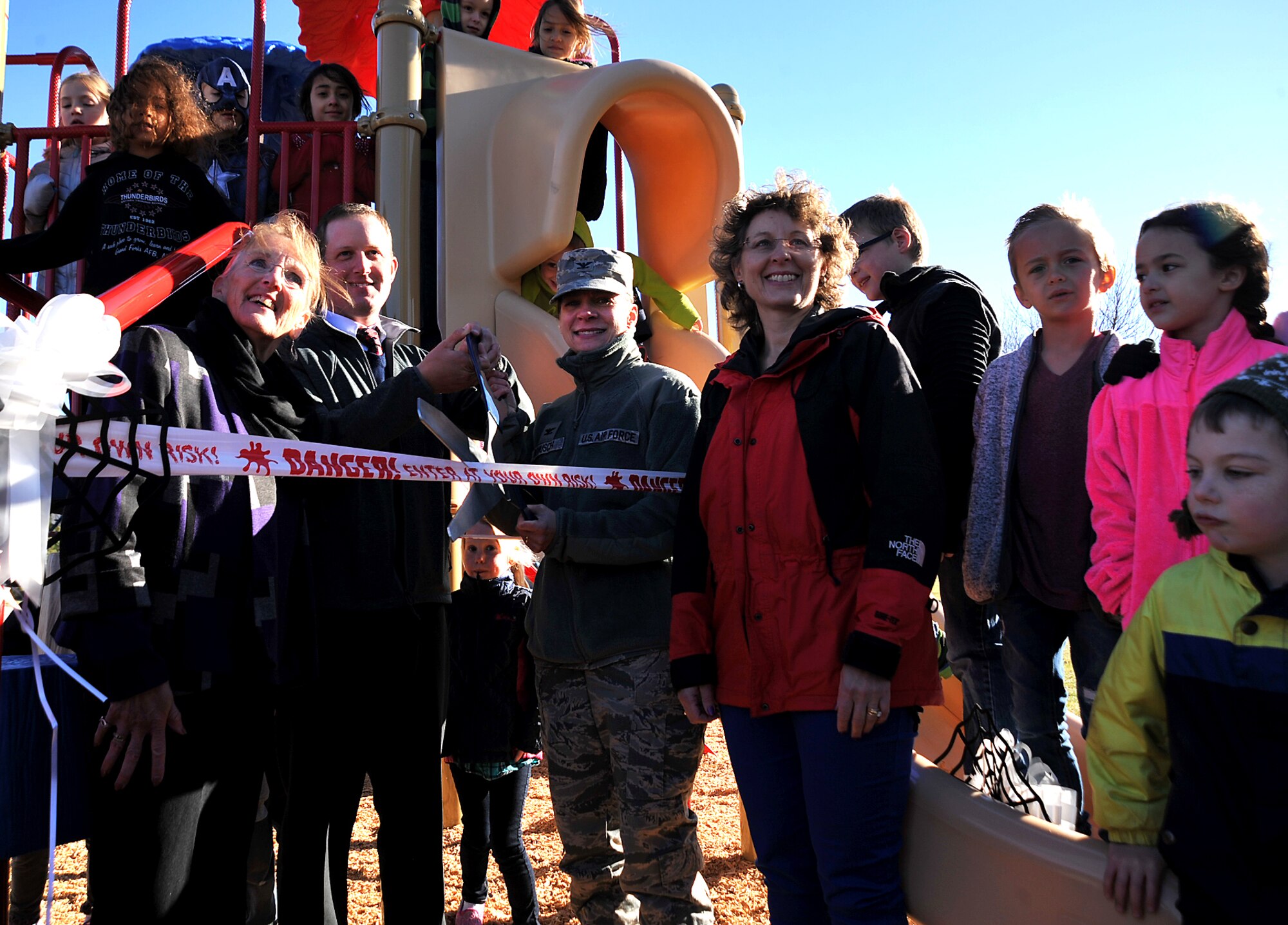 Timothy Haddock, Service Credit Union branch manager, and Col. Therese Bohusch, 319th Medical Group commander, cut the ribbon for the new playground donated by Service Credit Union to Twining Elementary and Middle School on Grand Forks Air Force Base, North Dakota, Oct. 15, 2015. The playground was designed for children ages 2-12 and for children with disabilities.(U.S. Air Force photo/Airman 1st Class Bonnie Grantham/Released)