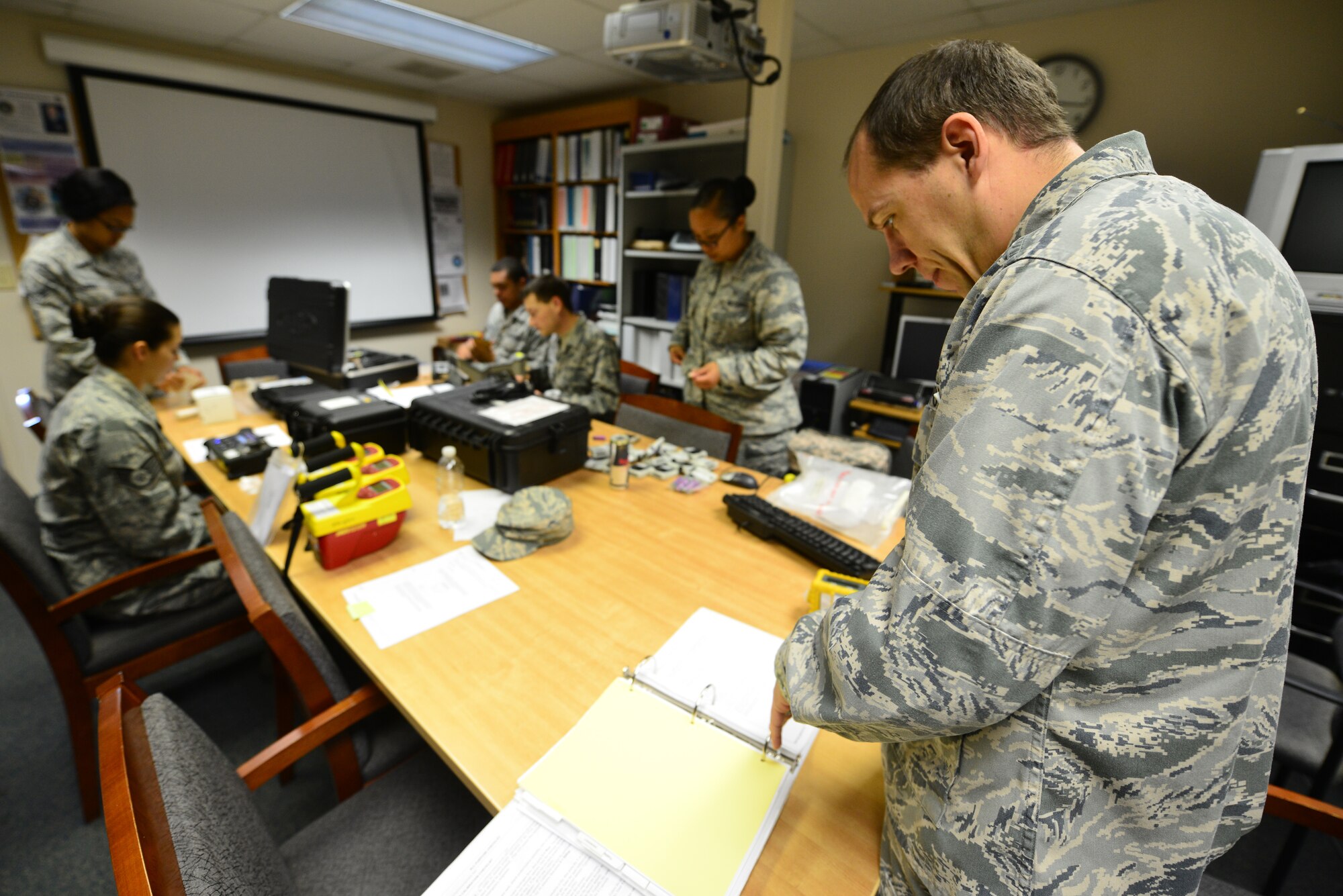 U.S. Air Force Capt. Patrick Morris, 633rd Aerospace Medicine Squadron bioenvironmental engineer, reviews inventory lists while bioenvironmental technicians check equipment functionality at Langley Air Force Base, Va., Oct. 8, 2015. The Airmen spent their training day conducting annual equipment inventory to guarantee their capability to identify community and workplace hazards. (U.S. Air Force photo by Senior Airman Aubrey White/Released)