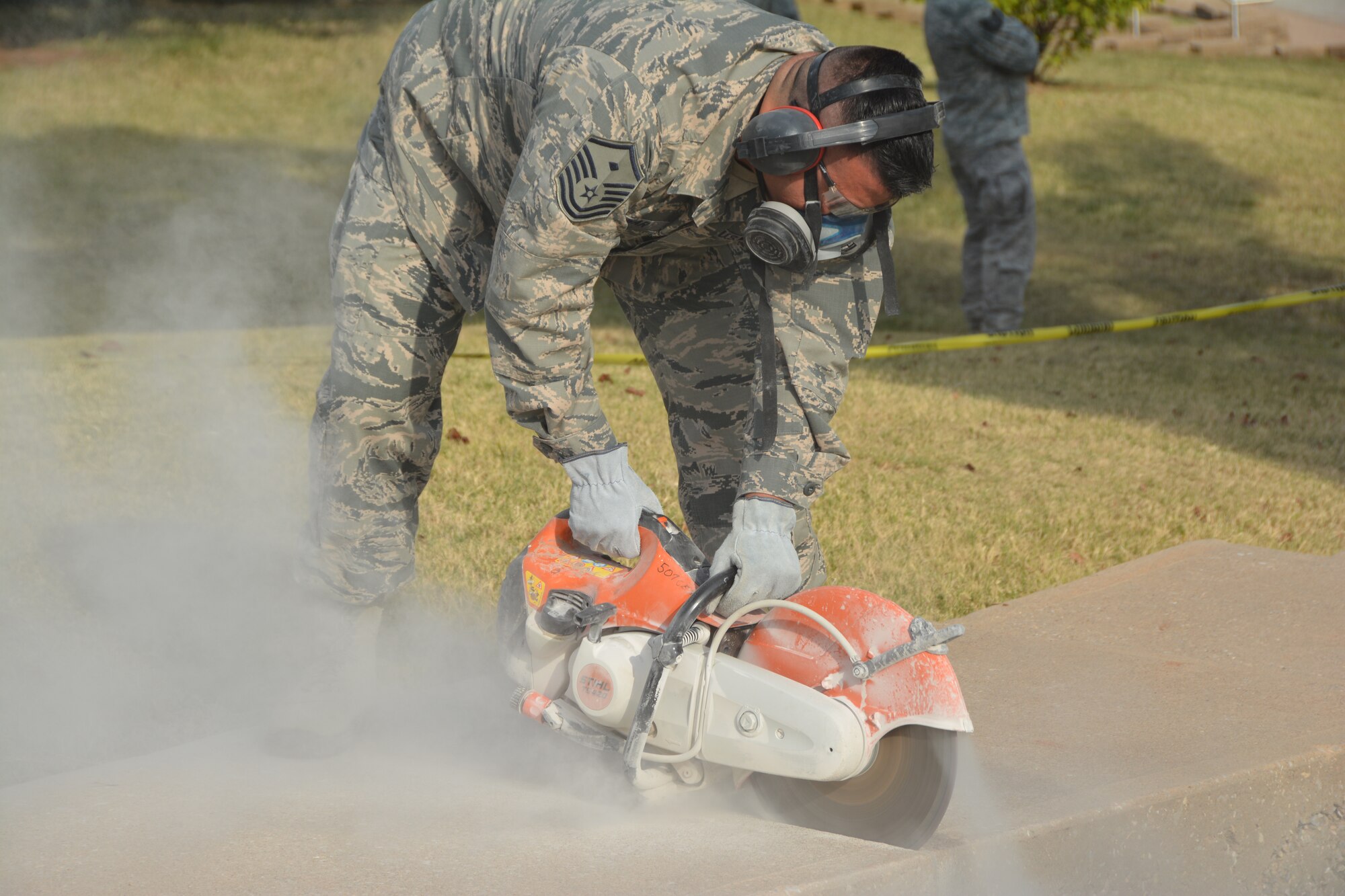 Master Sgt. Juan Escobar, 507th Civil Engineer 1st Sgt., cuts away at the sidewalk Oct. 3, 2015, at Tinker Air Force Base, Okla. The team used a combination of heavy equipment, circular saws and hand tools to tear out an unsafe concrete stairway, and covered the newly exposed earth with sod. (U.S. Air Force photo/Senior Airman Krystin Trosper)