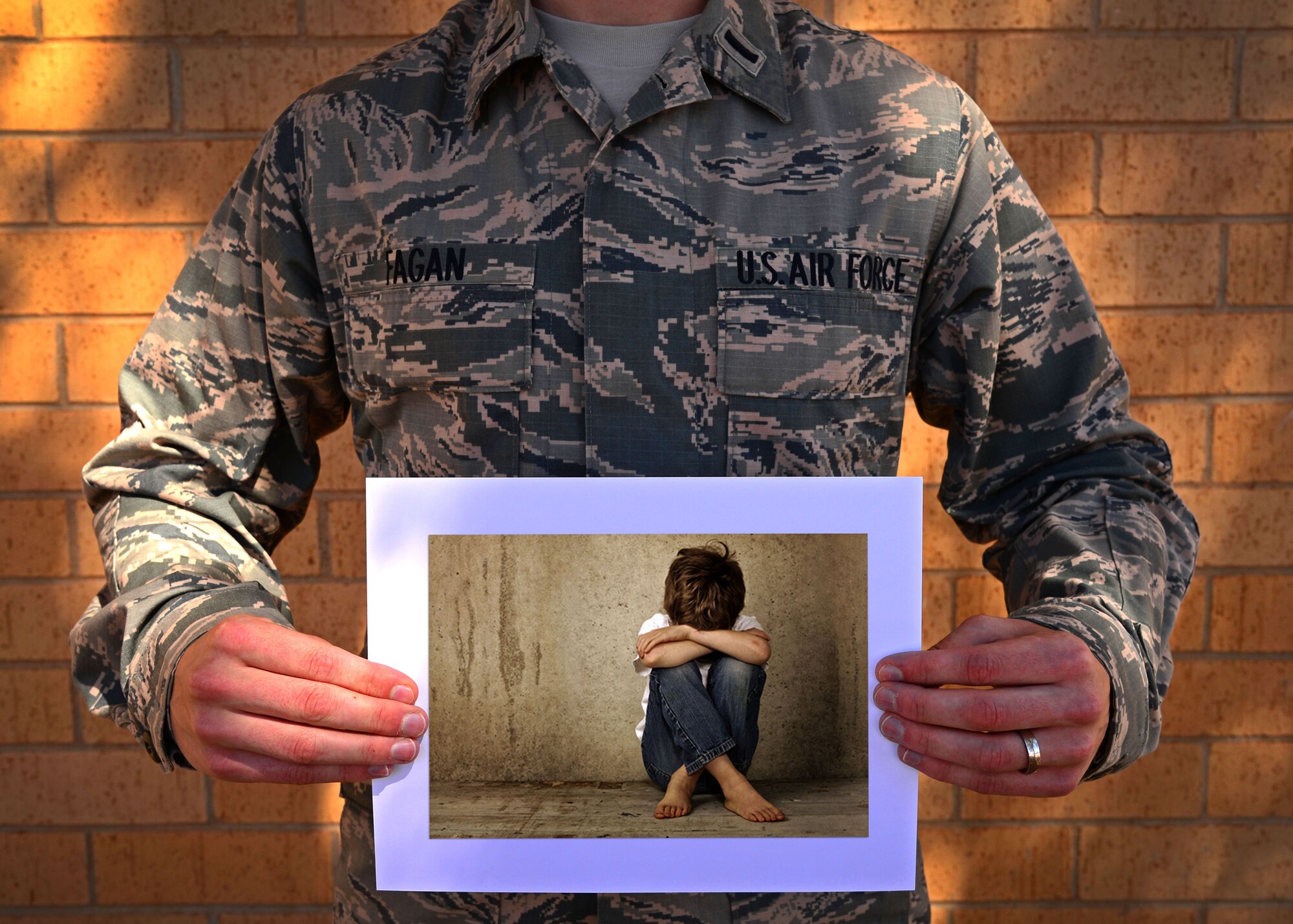 U.S. Air Force 1st Lt. Matthew Fagan, 56th Special Operations Intelligence Squadron, holds a photo illustration of a neglected child Oct. 14, 2015, at Cannon Air Force Base, N.M. Fagan was one of two Air Commandos sworn in as court-appointed special advocates for the New Mexico CASA Network and National CASA Association by the Honorable David Reeb on Oct. 6, 2015. (U.S. Air Force photo/Staff Sgt. Alexx Pons) 