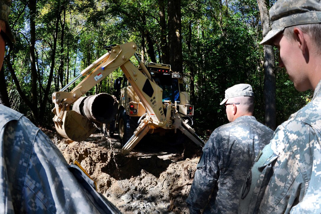 South Carolina Army National Spc. Brad Baughman operates an engineer excavator to remove sections of pipe on Boiling Springs Road, Lexington, S.C., during a statewide flood response, Oct. 14, 2015. Baughman is a horizontal construction engineer assigned to the South Carolina National Guard's 124th Engineer Company, 122nd Engineer Battalion. South Carolina Air National Guard photo by Airman Megan Floyd