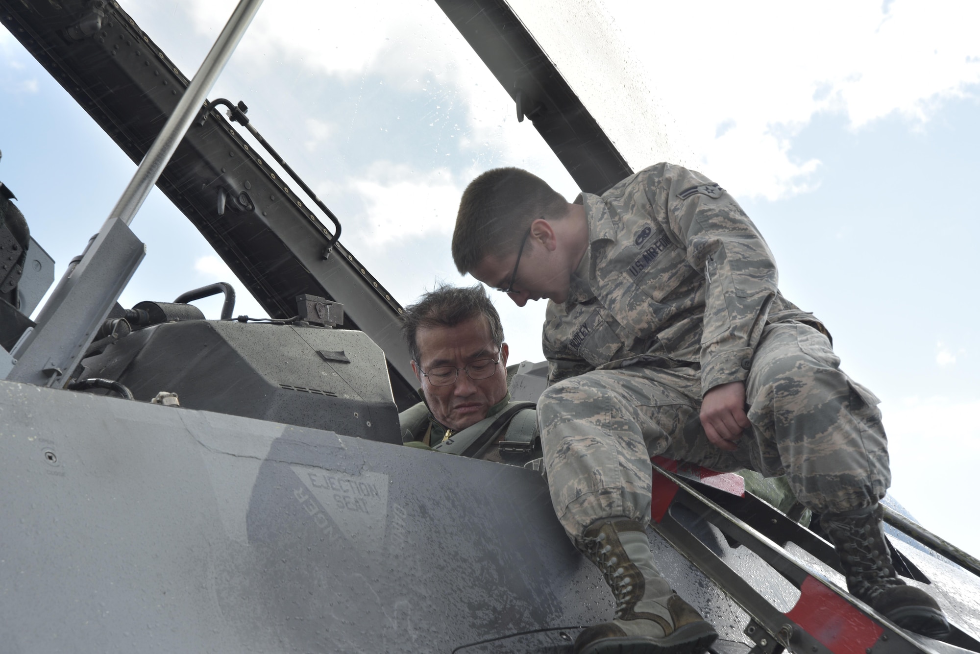 Airman 1st Class Jacob Dudley, a 35th Aircraft Maintenance Squadron crew chief, secures a strap on a seat for Japan Air Self-Defense Force Lt. Gen. Yoshiyuki Sugiyama, Air Defense Command commander, at Misawa Air Base, Japan, Oct. 14, 2015. Sugiyama was preparing to fly in an F-16 Fighting Falcon as part of a bilateral exchange flight with the 13th Fighter Squadron. (U.S. Air Force photo/Senior Airman Jose L. Hernandez-Domitilo)