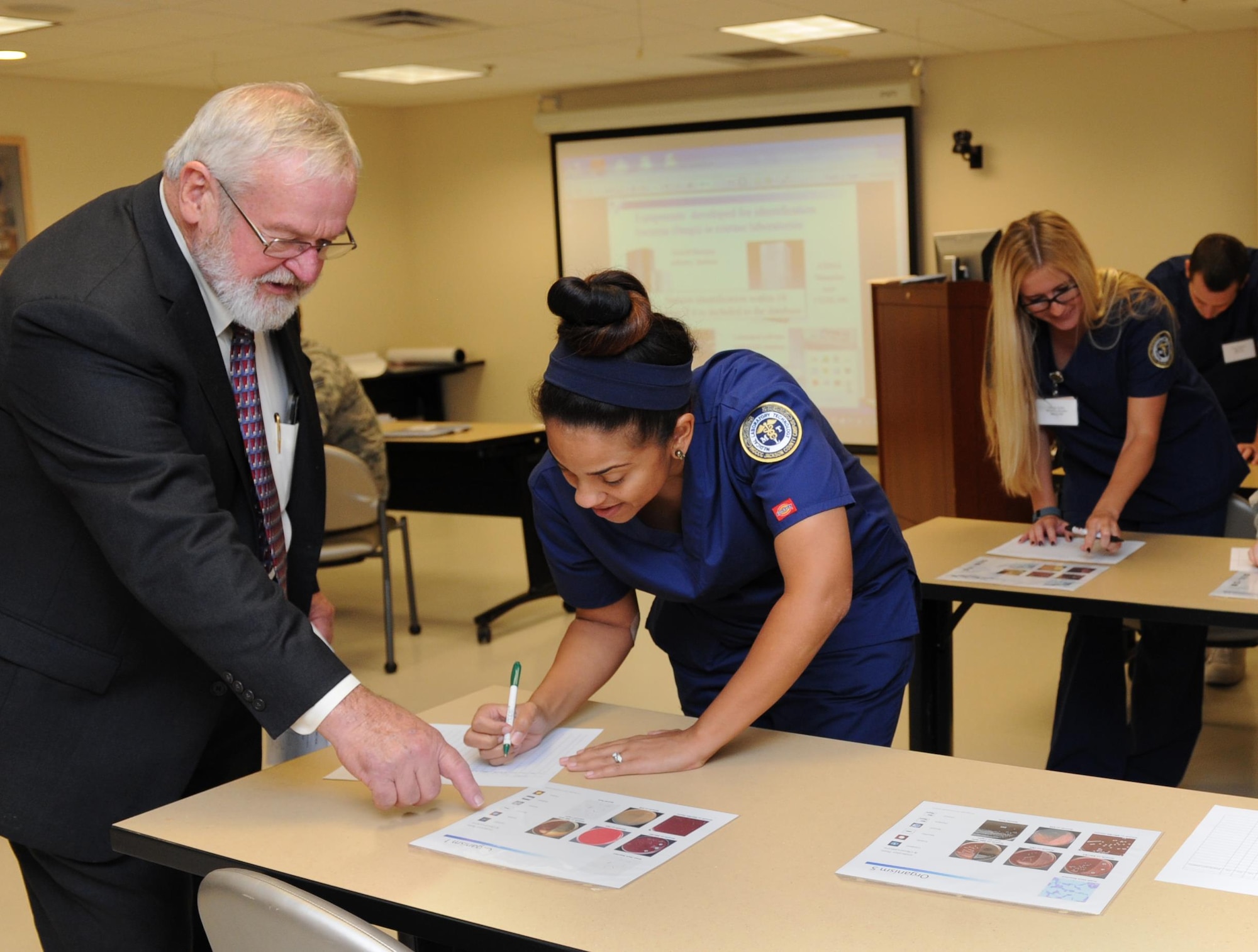 Mike Cox, Anaerobe Systems president, assists Kelli Goudy, Mississippi Gulf Coast Community College medical laboratory technician program student, with identifying various bacteria during an anaerobic bacteriology workshop at the Keesler Medical Center Oct. 13, 2015, Keesler Air Force Base, Miss. Seventeen individuals attended the one-day workshop which provided an update in anaerobic microbiology for the clinical laboratory. This is the first workshop of this kind to take place in the Air Force. (U.S. Air Force photo by Kemberly Groue)