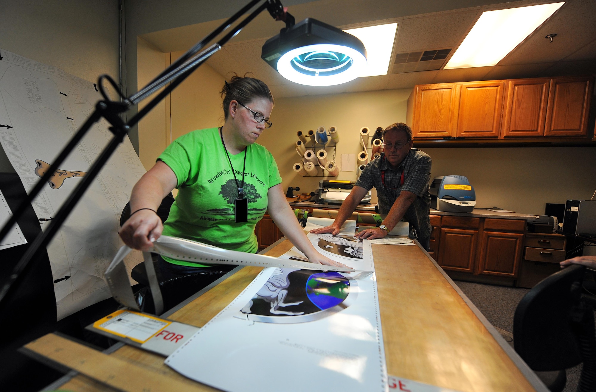 Angela Duncan, a sheet metal production controller with the 55th Maintenance Squadron, delicately removes excess vinyl from a newly printed nose art piece Sept. 21, 2015, at Offutt Air Force Base, Neb. Duncan takes existing art and formats it for the purpose of print production and applications to the aircraft. (U.S. Air Force photo illustration/Josh Plueger)