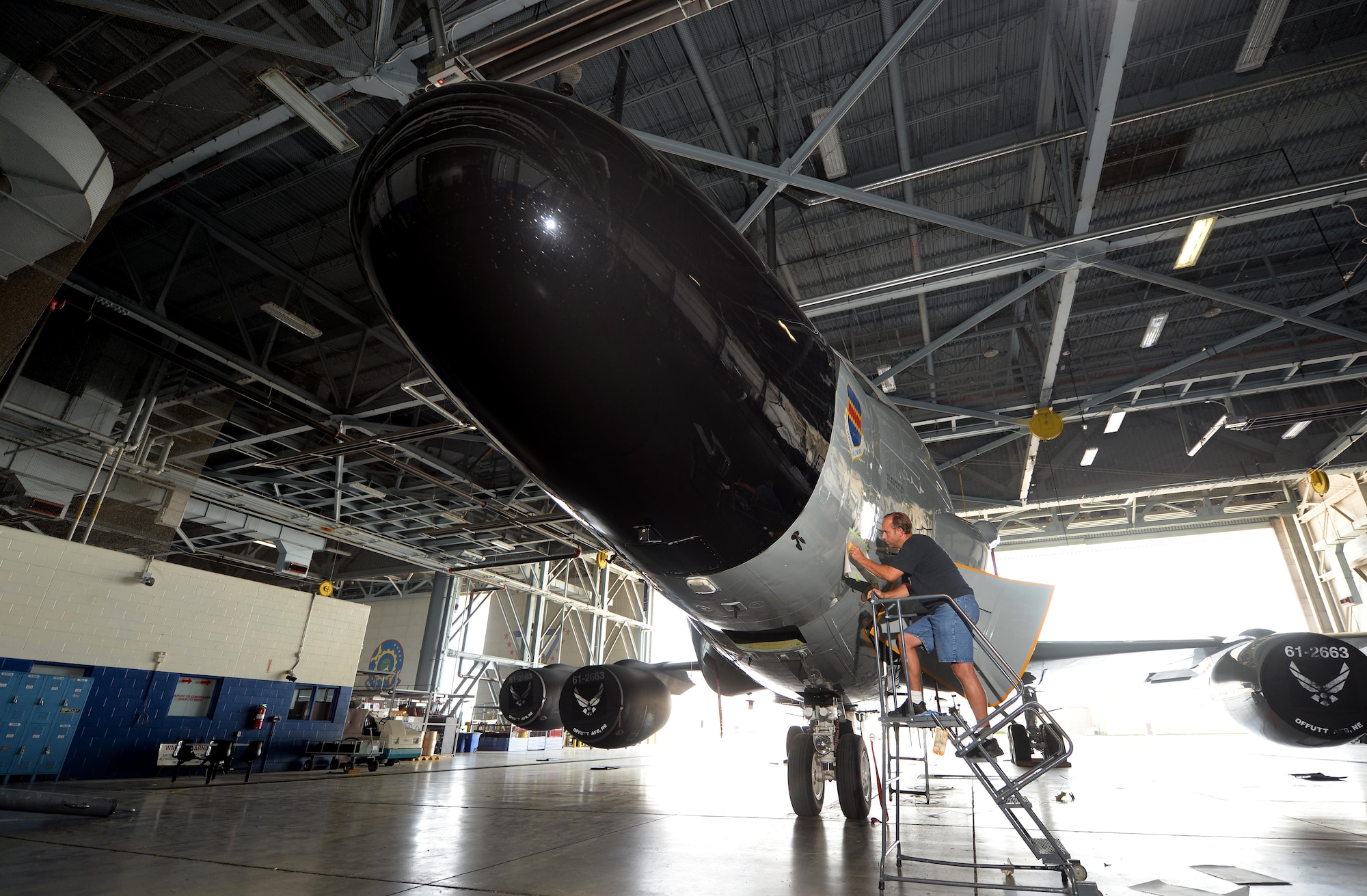 James Battig, a fabrication work leader with the 55th Maintenance Squadron, delicately places the first of many nose art pieces onto an RC-135S Cobra Ball Sept. 2, 2015, at Offutt Air Force Base, Neb. The Cobra Ball had the first higher headquarters approved art, a serpent tightly coiled around a black sphere. (U.S. Air Force photo/Josh Plueger)
