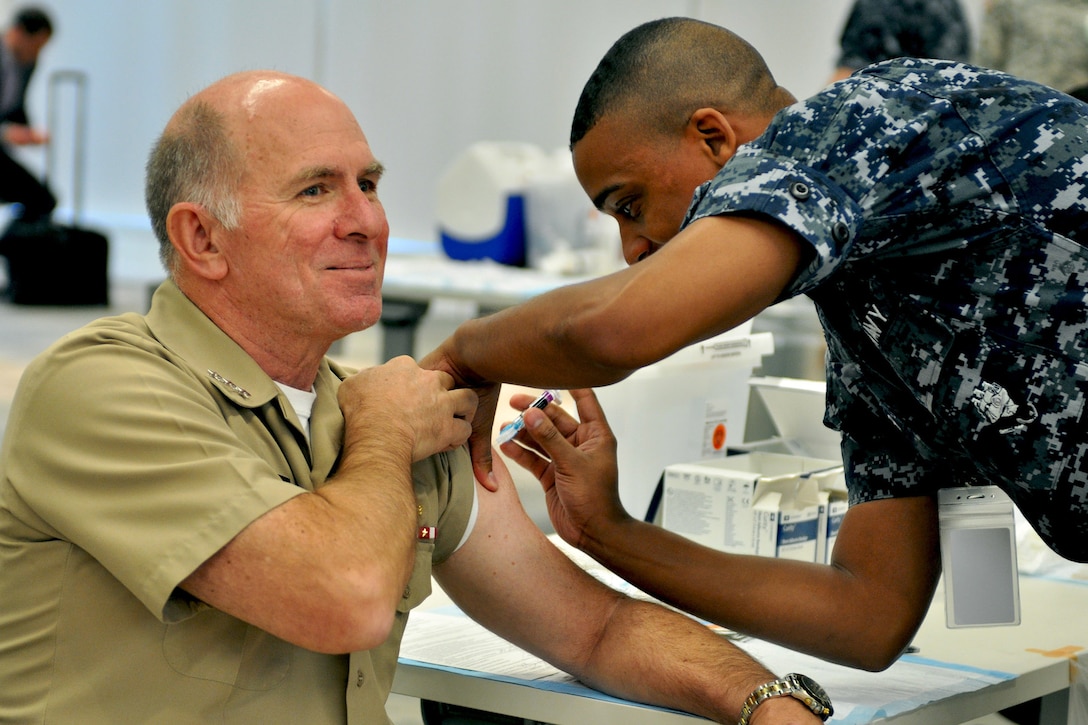 Navy Vice Adm. Matthew Nathan, Navy surgeon general and chief of the Bureau of Medicine and Surgery, receives his flu shot from Seaman Carl Parker Jr., at Defense Health Headquarters in Falls Church, Va., Oct. 15, 2015. U.S. Navy photo by James Rosenfelder