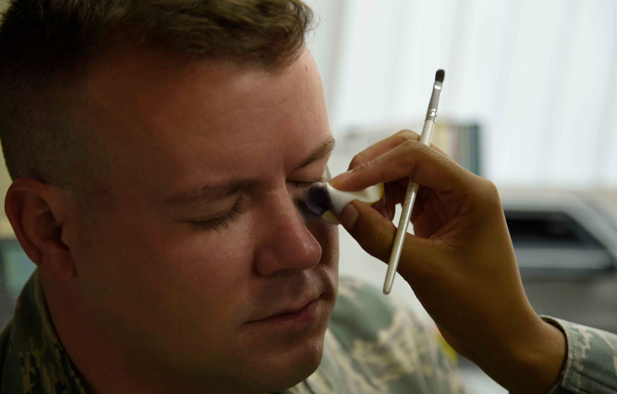 U.S. Air Force Senior Airman Augustine Thompson-Brown, 35th Medical Operations Squadron mental health technician, applies moulage to the eye of Staff Sgt. Joseph Bekaert, 35th Logistics Readiness Squadron fuels distribution supervisor, at Misawa Air Base, Japan, Oct. 15, 2015. This black eye makeup was part of a Domestic Violence Awareness Month campaign designed to bring the issue to light by getting the community involved. (U.S. Air Force photo by Airman 1st Class Jordyn Fetter/Released) 