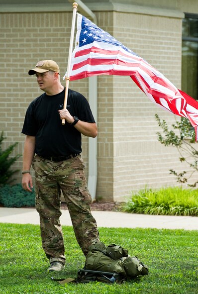Senior Master Sgt. David Jackson, 512th Force Support Squadron education and training, holds the American flag before he participates in the GORUCK Light event. GORUCK events are team challenges where participants are placed in a formation with rucksacks varying in different weight with the objective to cover a certain distance in a designated amount of time, all while completing vigorous PT sessions and carrying heavy objects. (U.S. Air Force photo/Roland Balik)