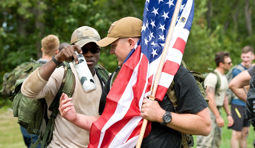 Senior Master Sgt. David Jackson, 512th Force Support Squadron education and training, grabs a drink of water from his wingman during a break at the GORUCK Light event. GORUCK events are team challenges where participants are placed in a formation with rucksacks varying in different weight with the objective to cover a certain distance in a designated amount of time, all while completing vigorous PT sessions and carrying heavy objects. (U.S. Air Force photo/Roland Balik)
