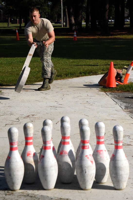 Airman 1st Class John Stapleton, 4th Civil Engineer Squadron explosive ordnance disposal technician, attempts to bowl a strike with a fire hose during a firefighter challenge as part of Fire Prevention Week, Oct. 9, 2015, at Seymour Johnson Air Force Base, North Carolina. The winner of the competition was determined by who completed the course with the fastest time, with a one second time reduction for each pin knocked over. (U.S. Air Force photo/Senior Airman Brittain Crolley)
