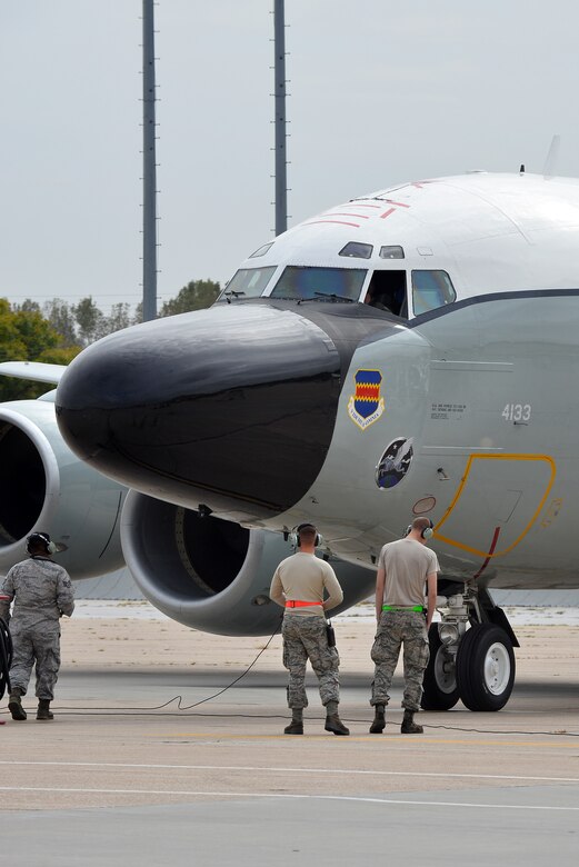 Airmen with the 55th Maintenance Squadron marshal an RC-135V/W Rivet Joint adorned with the Pegasus nose art down the flight line, Oct. 6, Offutt Air Force Base, Neb.  Commissioned art work will soon become a part of the runway landscape as the RC inventory get custom nose art.  (U.S. Air Force photo Illustration by Josh Plueger/Released)