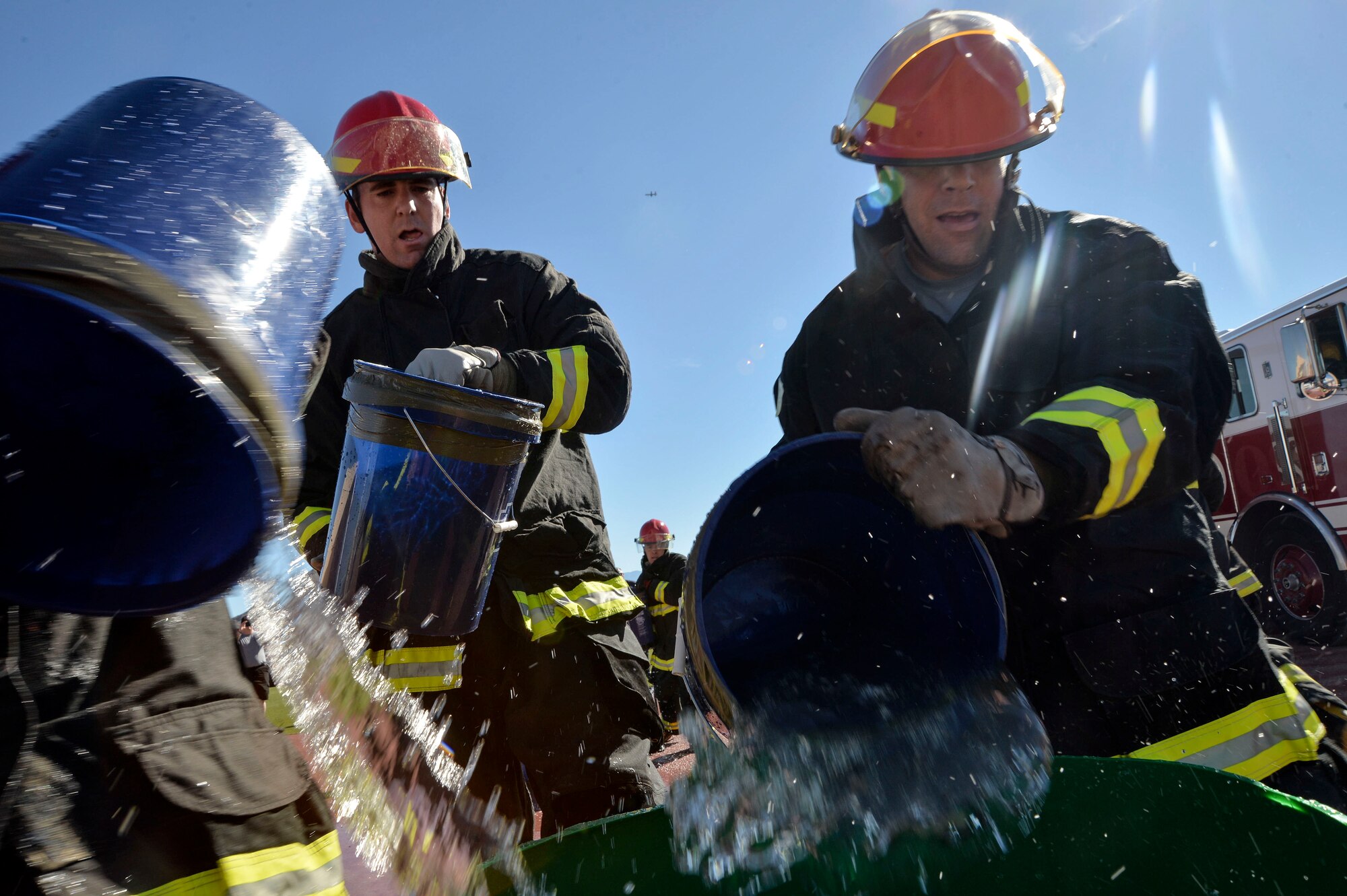 Airmen of Team Creech pour buckets of water into container at Creech Air Force Base, Nevada, Oct. 9, 2015. Over 12 teams competed in the event, which aims to spread fire prevention awareness through a series of firefighter related challenges.  (U.S. Air Force photo by Senior Airman Adarius Petty)