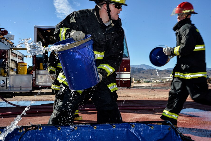 An Airman from Team Creech fills bucket as a part of a challenge at Creech Air Force Base, Nevada, Oct. 9, 2015. The Fire Muster challenge was a part of the Fire Prevention month, 12 teams participated in this challenge. (U.S. Air Force photo by Senior Airman Adarius Petty)