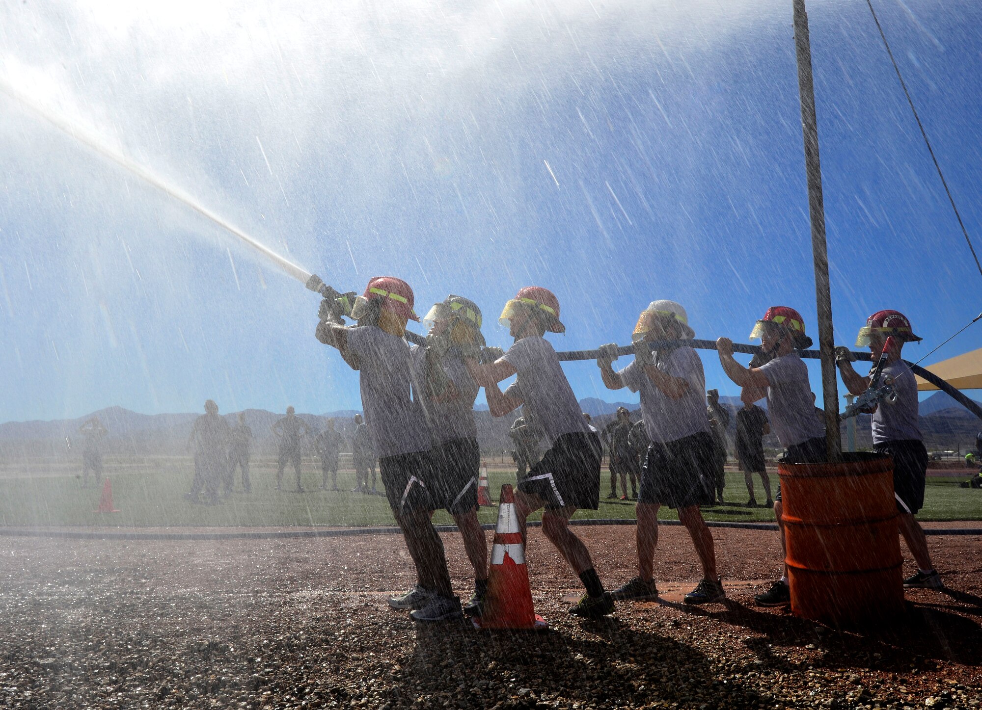 A team of Airmen compete in the finals of the 2015 Fire Muster Oct. 9, 2015, at Creech Air Force Base, Nevada. The teams had to spray a barrel across a line to the other team's side to win the 5th annual Fire Muster trophy. (U.S. Air Force photo by Airman 1st Class Christian Clausen/Released)