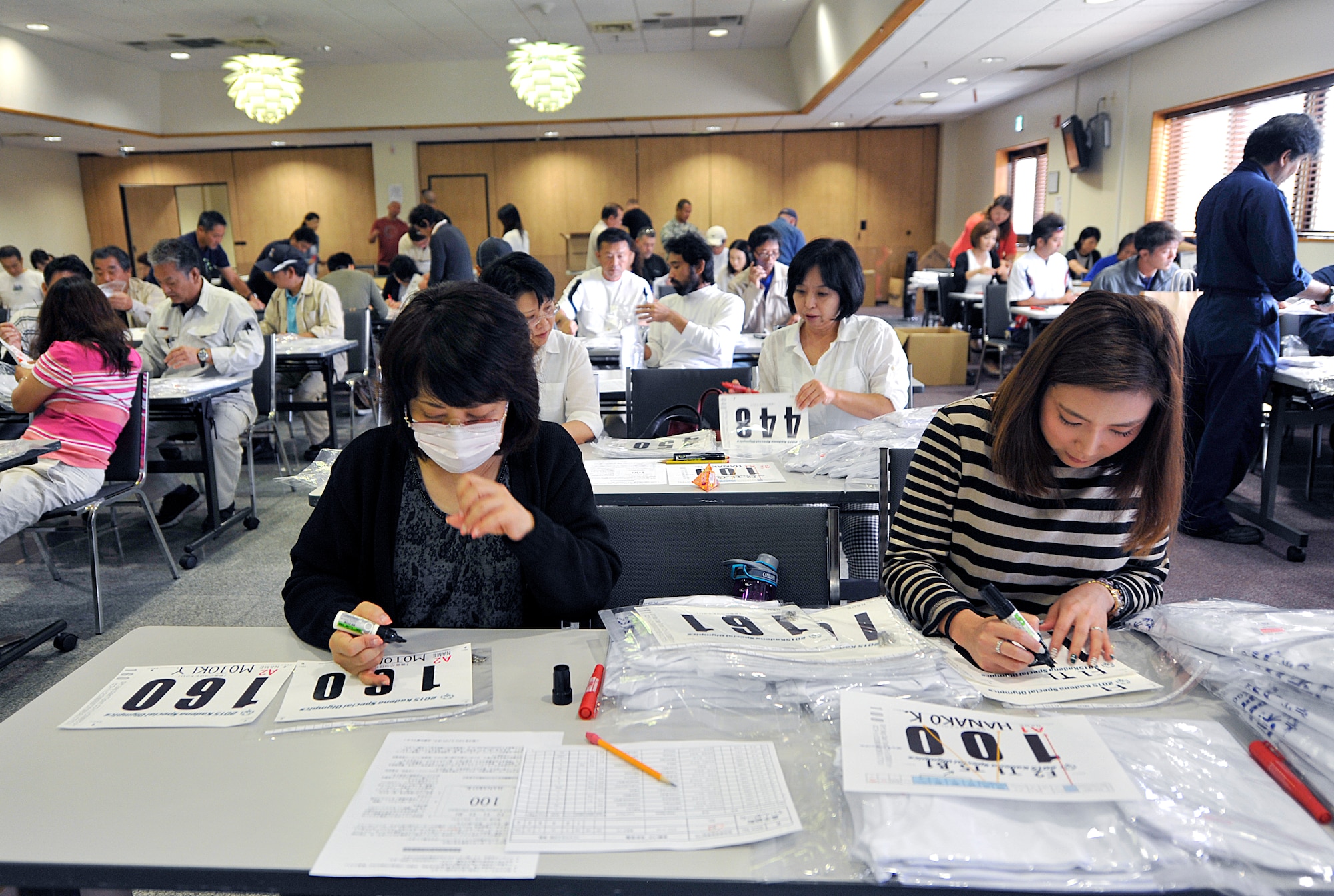 Approximately 70 volunteers prepare for the upcoming 16th annual Kadena Special Olympics at the Schilling Community Center on Kadena Air Base, Japan, Oct. 16, 2015. Volunteers worked to create sports bibs displaying the athlete's name, participant number and the events in which they will compete. (U.S. Air Force photo by Naoto Anazawa)