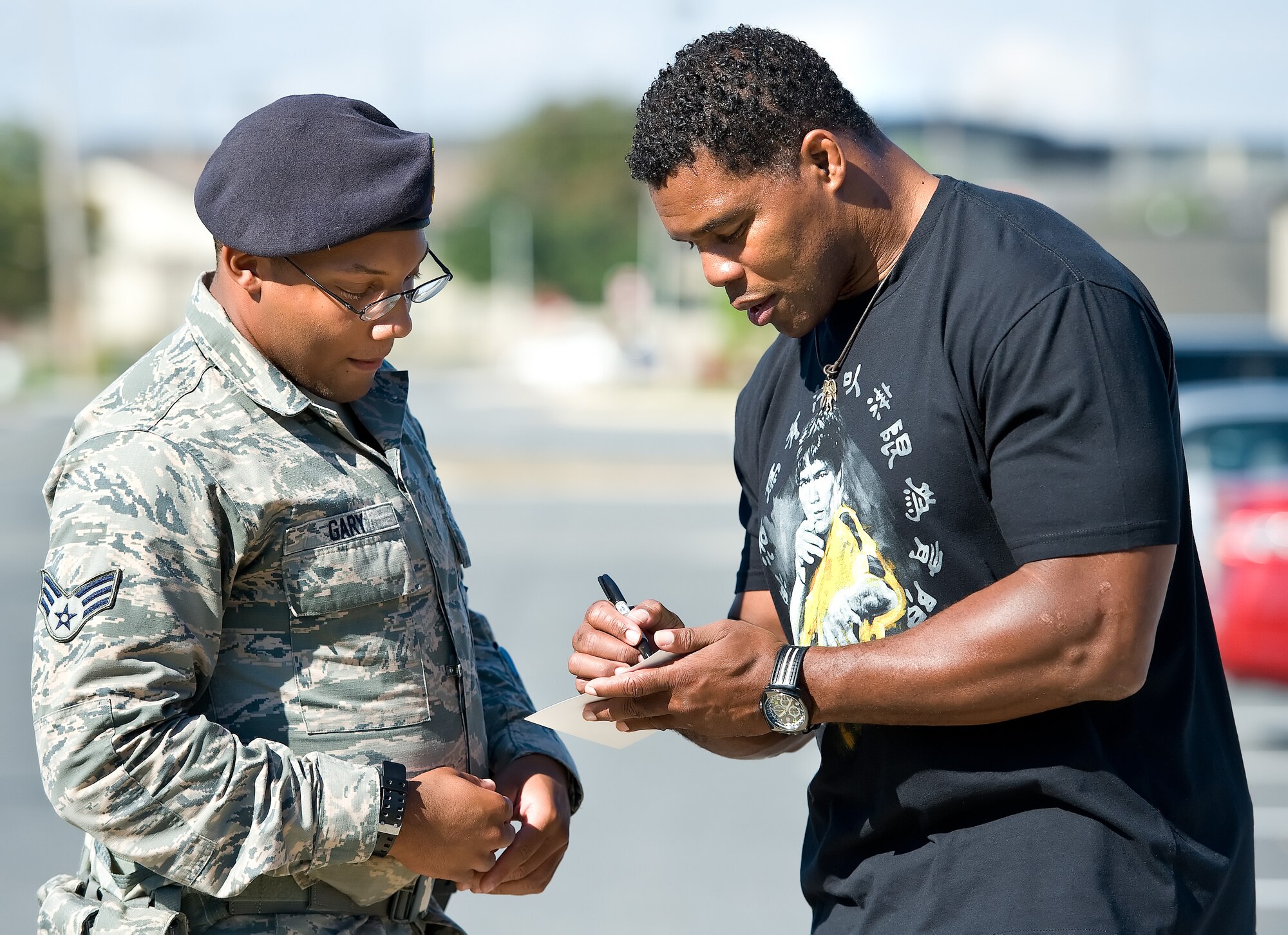 Former NFL running back and 1982 Heisman Trophy winner Herschel Walker, right, autographs a photo for Senior Airman Vernon Gary, 512th Security Forces Squadron response force leader, left, Oct. 13, 2015, on Dover Air Force Base, Del. At each stop on his base tour, Walker autographed photos and answered personal and sports-related questions from Team Dover members. (U.S. Air Force photo/Roland Balik)