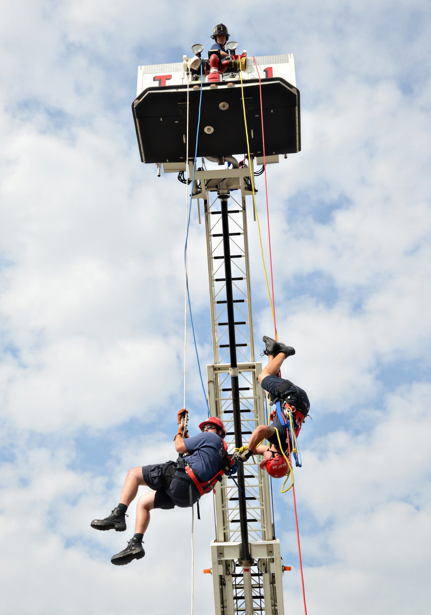 From left, Tinker Fire and Emergency Services Lieutenants Jason Culver and Jeff Briley demonstrate a high angle pick-off rescue off of the ladder truck which was raised 50 feet in the air at the Base Exchange on Oct. 8. Lieutenant Briley rappelled to Lieutenant Culver, who was acting in the victim role, to “pick off,” or transfer him, from his rope onto Lieutenant Briley’s rescue rope. The firefighters receive special training to learn these techniques. The rope rescue was one of the highlights of Fire Prevention Week. (Air Force photos by Kelly White/Released)
