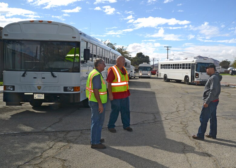 From left to right: Steven Schlecht, James Boyer and Juan Lopez of the 412th Logistics Readiness Squadron, prepare to head back to Edwards AFB following a very early work day where they were called to assist Kern County Sheriff's Department and California Highway Patrol with transporting stranded motorists to shelters in the local area such as this one at Mojave High School. The motorists became stranded on SR 58 following heavy rainstorms that triggered a mudslide during the evening hours of Oct. 15. The 412th LRS provided four buses and drivers to help transport victims to local shelters. (U.S. Air Force photo by Kenji Thuloweit)