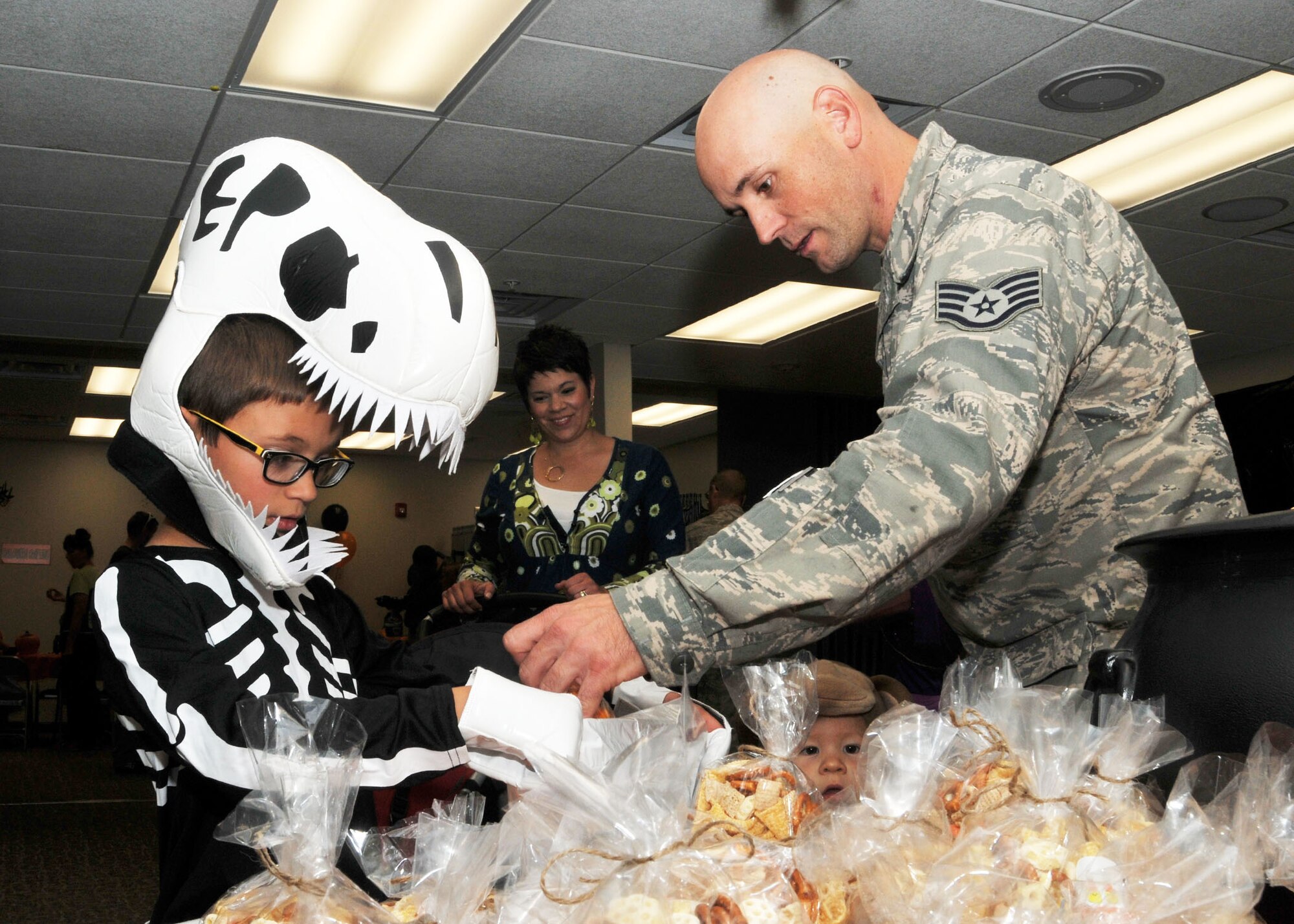 A child dressed as a dinosaur receives a treat from his father during the Montana Air National Guard Airman and Family Readiness Program Halloween party held for children of guardsmen at the 120th Airlift Wing in Great Falls, Mont., Oct. 14, 2015. (U.S. Air National Guard photo by Senior Master Sgt. Eric Peterson/Released) 