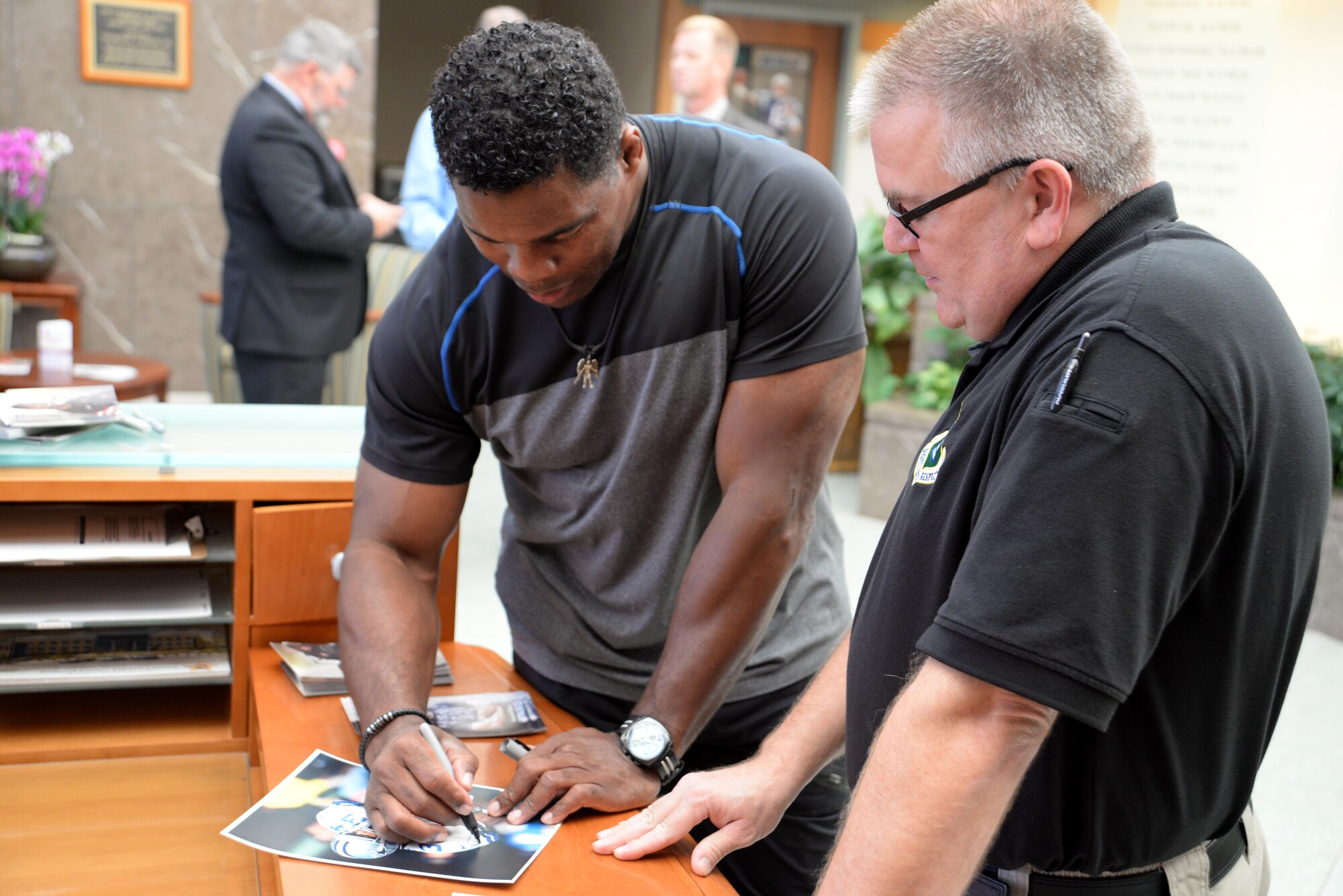 Former NFL player, Herschel Walker signs an autograph for Ed Conway, Air Force Mortuary Affairs Operations mortuary specialist, during a visit Oct. 15, 2015 to the Charles C. Carson Center for Mortuary Affairs, Dover Air Force Base, Del. Walker expressed his gratitude to the men and women of AFMAO for the work they do for the nation’s fallen service members. (U.S. Air Force photo/Tech. Sgt. Jose Contreras)