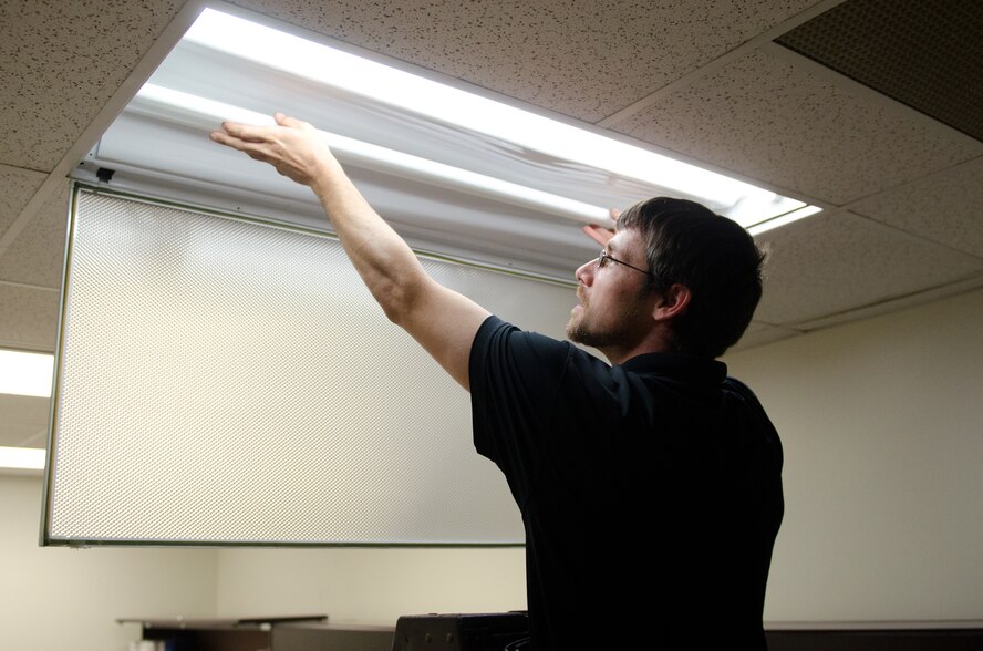 Darren Schroerluke, an installation technician for Eco-Engineering, installs new lights into a fixture at the Kentucky Air National Guard Base in Louisville, Ky., June 3, 2015. The base is undergoing a lighting upgrade that will increase energy efficiency by more than 30 percent. (Kentucky Air National Guard photo by Master Sgt. Phil Speck)