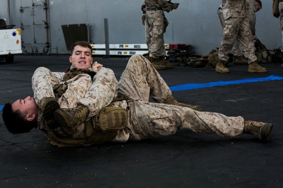 ARABIAN GULF (Oct. 16, 2015) U.S. Marines with Lima Company, Battalion Landing Team 3rd Battalion, 1st Marine Regiment, 15th Marine Expeditionary Unit, grapple during a deck shoot aboard the amphibious assault ship USS Essex (LHD 2). The Marines grappled between courses of fire to practice shooting with an increased heart rate. The 15th MEU, embarked aboard the ships of the Essex Amphibious Ready Group, is deployed to maintain regional security in the U.S. 5th Fleet area of operations. (U.S. Marine Corps photo by Cpl. Anna Albrecht/Released)