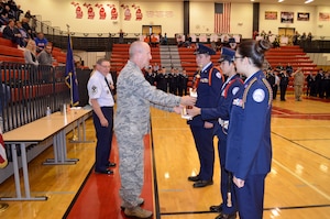Brig. Gen. John D. Slocum, commander of the 127th Wing, presents an award to three Anchor Bay Junior ROTC cadets that came together for drill team competitions on Otc. 17, 2015, at Anchor Bay High School in Michigan. Ten teams of approximately 25 cadets meet to compare professional abilities against one another exhibiting the capability to work as a team, perform in a stressful environment, and display discipline.