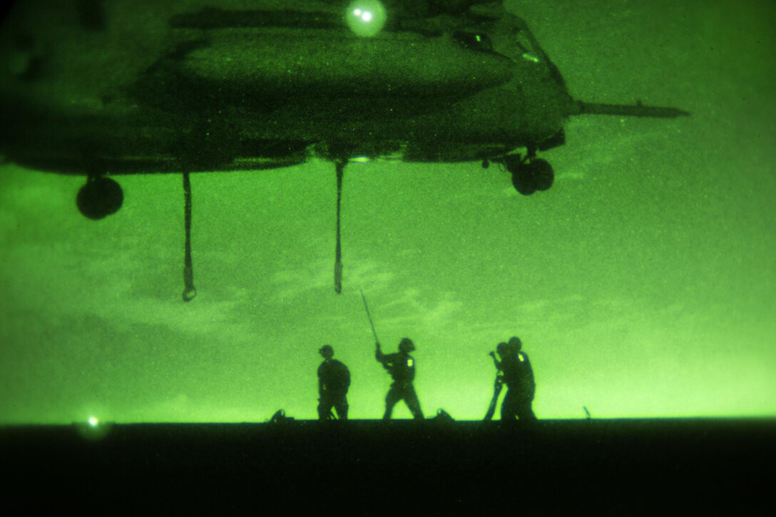 As seen through a night-vision device, Marines prepare to hook onto a sling line attached to a Marine Corps CH-53E Super Stallion helicopter during external lift training at Marine Corps Air Station Miramar, Calif., Oct. 14, 2015. The Marines are assigned to Combat Logistics Battalion 13 and the helicopter crew is assigned to Marine Medium Tiltrotor Squadron 166 Reinforced, 3rd Marine Aircraft Wing. U.S. Marine Corps photo by Sgt. Brian Marion