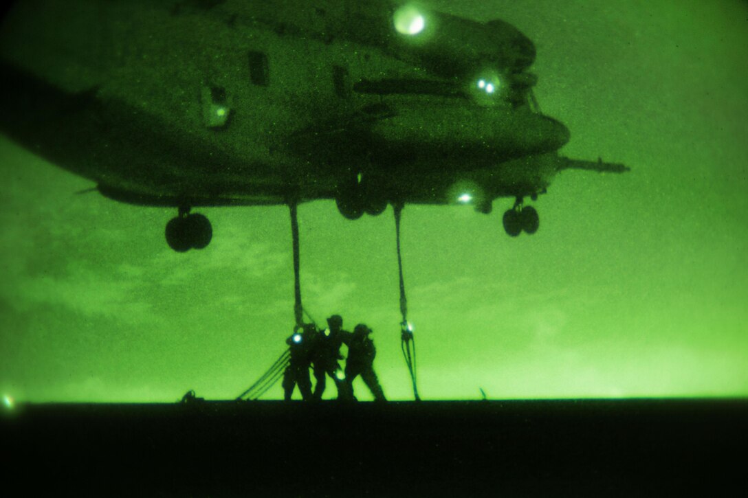 As seen through a night-vision device, Marines attach a 6,200 pound steel girder to a Marine Corps CH-53E Super Stallion helicopter during external lift training at Marine Corps Air Station Miramar, Calif., Oct. 14, 2015. U.S. Marine Corps photo by Sgt. Brian Marion