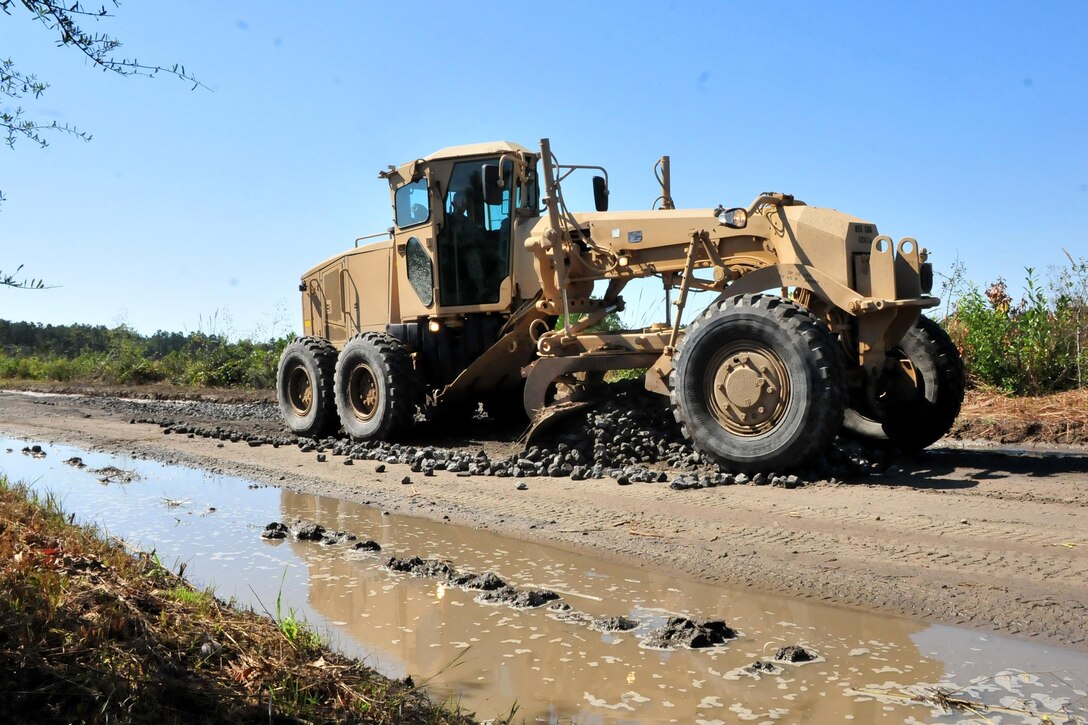 A North Carolina National Guardsman operates a road grader and pushes gravel for a newly formed road, while Indian Hut Road is rebuilt in Andrews, S.C. on Oct. 16, 2015. North Carolina Army National Guard photo