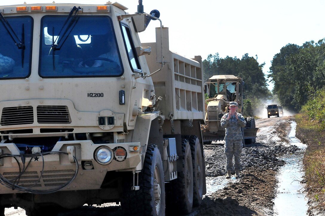 A North Carolina National Guardsman directs a 10-ton dump truck to help repair multiple sections of Indian Hut Road in Andrews, South Carolina, Oct. 16, 2015. North Carolina Army National Guard photo by Sgt. Ason Forsyth
