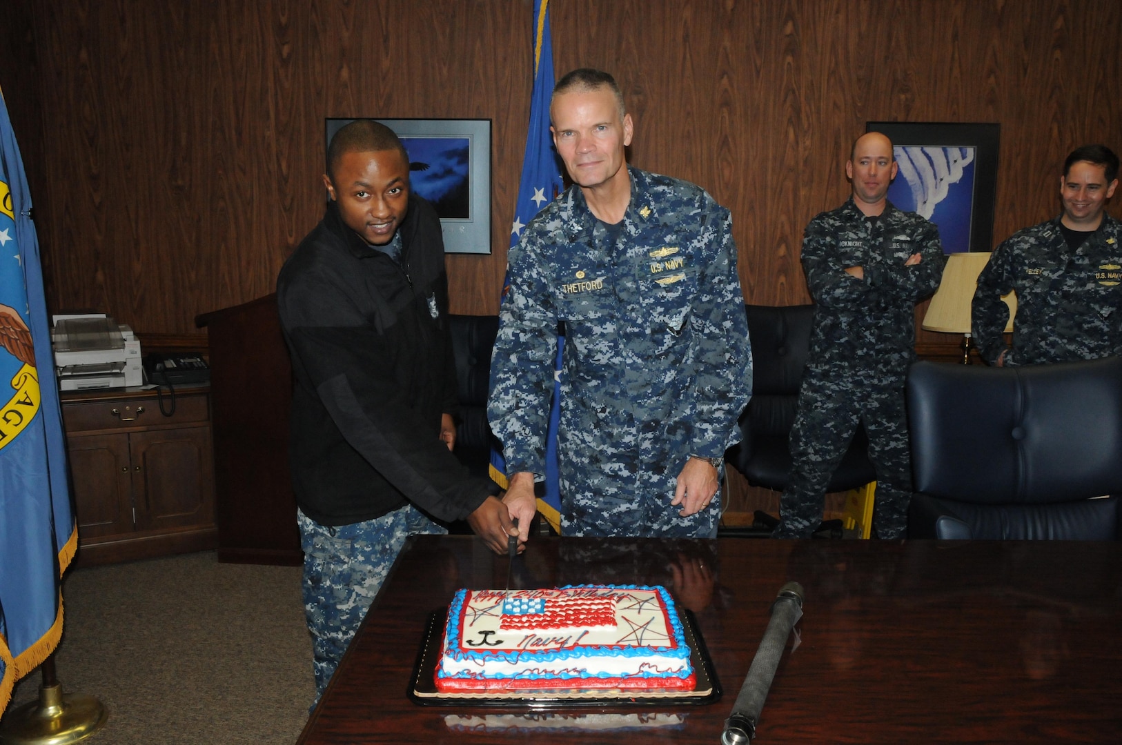 Shipmates at DLA Distribution Norfolk, Va., including LS1 Daniel Cordero, Lt. Matthew Kelley, QM1 Andrew McKnight, Capt. Harry Thetford (DLA Distribution Norfolk’s commander), LS2 Dana Plummer, Lt. Cmdr. Chris Mayfield, and Lt. Emmanuel Nneji, cut a cake honoring the 240th birthday of the Navy. In tradition, the cake was cut with the oldest and youngest members of the command.
