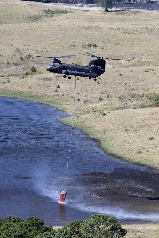 A Texas Army National Guard CH-47 Chinook helicopter refills a bucket firefighting system in a lake before continuing fighting wildfires threatening homes and property near Bastrop, Texas, Oct. 14, 2015. Texas Air National Guard photo by 1st Lt. Alicia Lacy