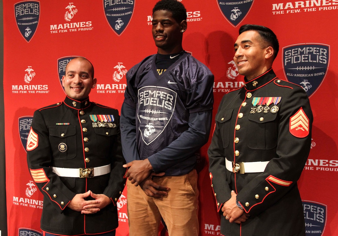 Bullis School senior, Cameron Brown, stands with U.S. Marine Corps Staff Sgt. Raymond Guzman-Ortiz, left, and Sgt. William Ramos-Sorto, right, recruiters with Recruiting Sub-station Rockville during Brown’s Semper Fidelis All-American Bowl selection jersey presentation Oct. 13, 2015, at Bullis School auditorium in Potomac, Maryland. The Semper Fidelis Football Program focuses on mentoring exceptional youth athletes and future leaders by collectively celebrating academic excellence, proven physical fitness and quality of character. Brown, from Burtonsville, Maryland, will play in the televised game Jan. 3, 2016 in Carson, California. (U.S. Marine Corps photo by Sgt. Anthony J. Kirby/Released)