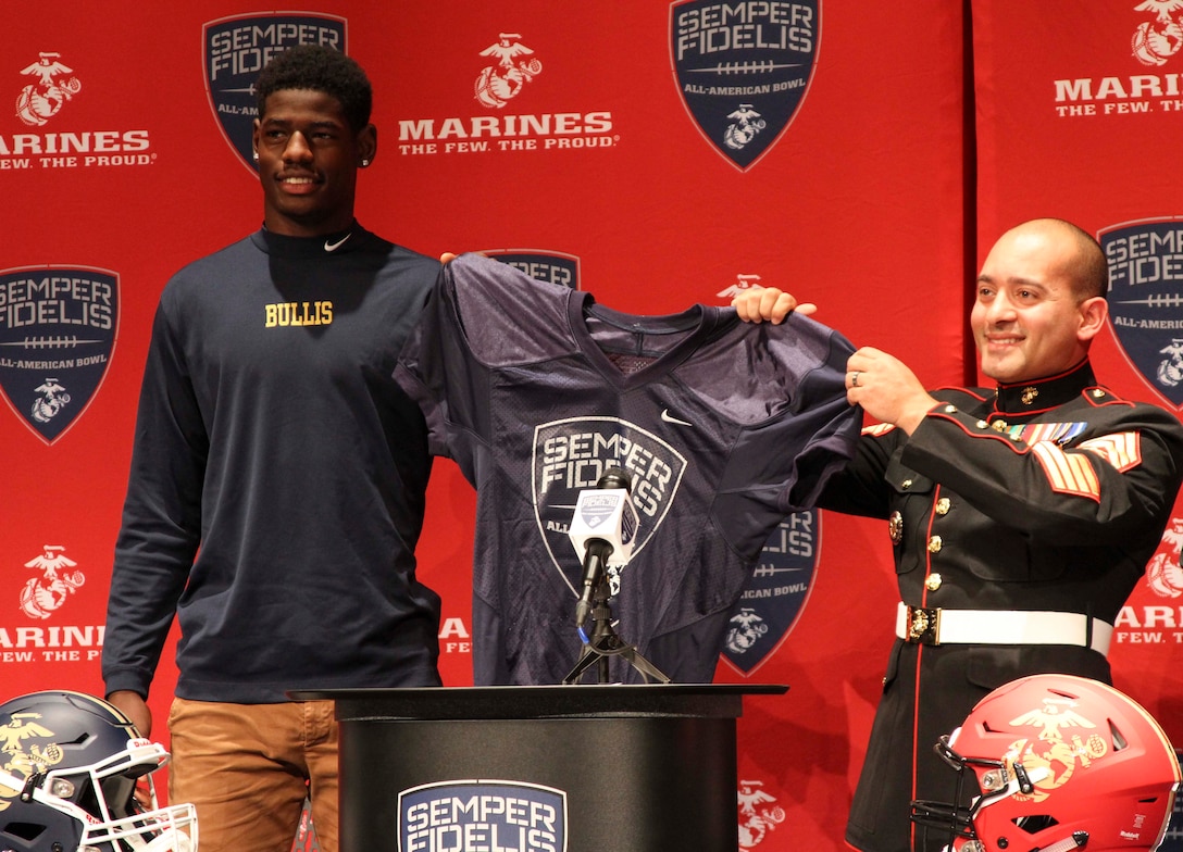 Bullis School senior football player, Cameron Brown, is presented with his Semper Fidelis All-American Bowl selection jersey by U.S. Marine Corps Staff Sgt. Raymond Guzman-Ortiz during a selection presentation Oct. 13, 2015, at Bullis School auditorium in Potomac, Maryland. The Semper Fidelis Football Program focuses on mentoring exceptional youth athletes and future leaders by collectively celebrating academic excellence, proven physical fitness and quality of character. Brown, from Burtonsville, Maryland, will play in the televised game Jan. 3, 2016 in Carson, California. (U.S. Marine Corps photo by Sgt. Anthony J. Kirby/Released)