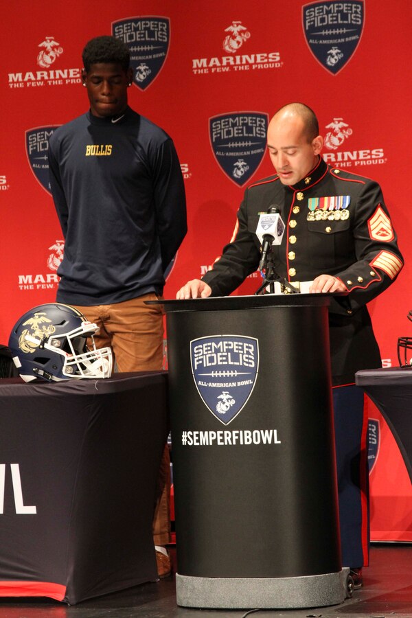 Bullis School senior football player, Cameron Brown, is presented with his Semper Fidelis All-American Bowl selection jersey by U.S. Marine Corps Staff Sgt. Raymond Guzman-Ortiz during a selection presentation Oct. 13, 2015, at Bullis School auditorium in Potomac, Maryland. The Semper Fidelis Football Program focuses on mentoring exceptional youth athletes and future leaders by collectively celebrating academic excellence, proven physical fitness and quality of character. Brown, from Burtonsville, Maryland, will play in the televised game Jan. 3, 2016 in Carson, California. (U.S. Marine Corps photo by Sgt. Anthony J. Kirby/Released)