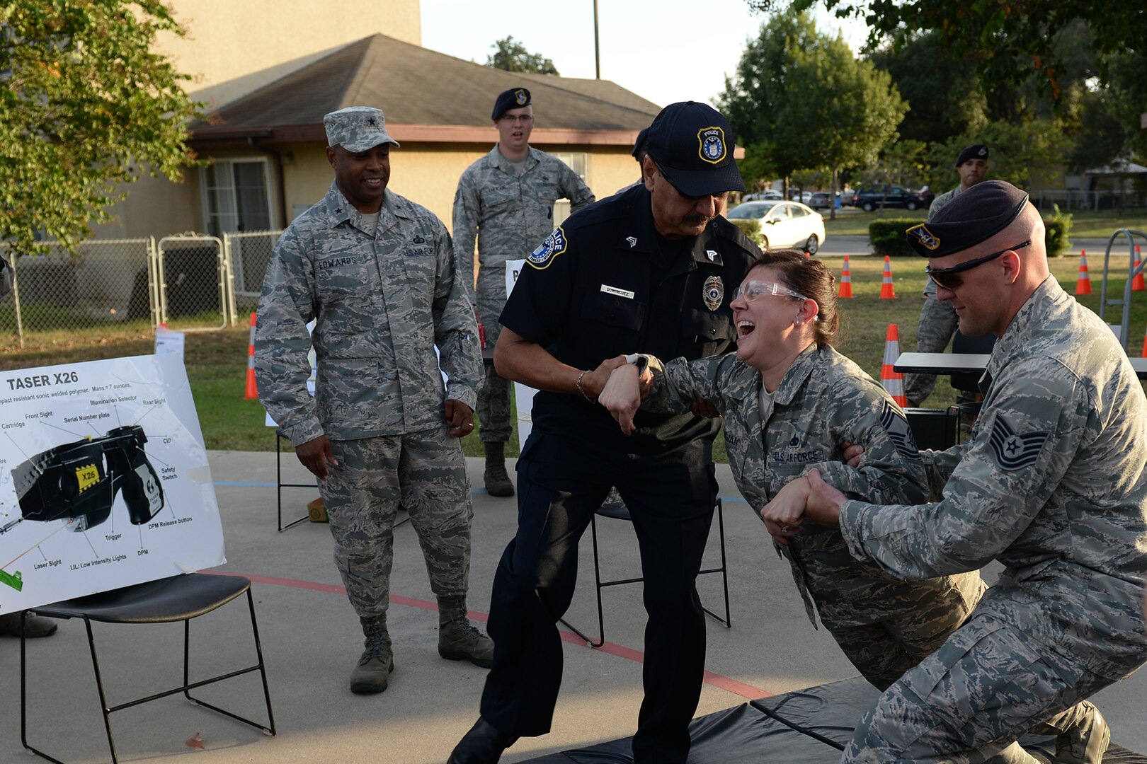 Chief Master Sgt. Lori Gawan, 502nd Installation Support Group superintendent and volunteer, is tasered as part of a Taser demonstration while Brig. Gen. Trent Edwards, 37th Training Wing commander, watches during National Night Out Oct. 6, 2015, at Joint Base San Antonio-Lackland, Texas. The annual event is nation-wide neighborhood crime and drug prevention event. (U.S. Air Force photo by Senior Airman Krystal Wright/Released)