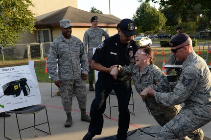 Chief Master Sgt. Lori Gawan, 502nd Installation Support Group superintendent and volunteer, is tasered as part of a Taser demonstration while Brig. Gen. Trent Edwards, 37th Training Wing commander, watches during National Night Out Oct. 6, 2015, at Joint Base San Antonio-Lackland, Texas. The annual event is nation-wide neighborhood crime and drug prevention event. (U.S. Air Force photo by Senior Airman Krystal Wright/Released)