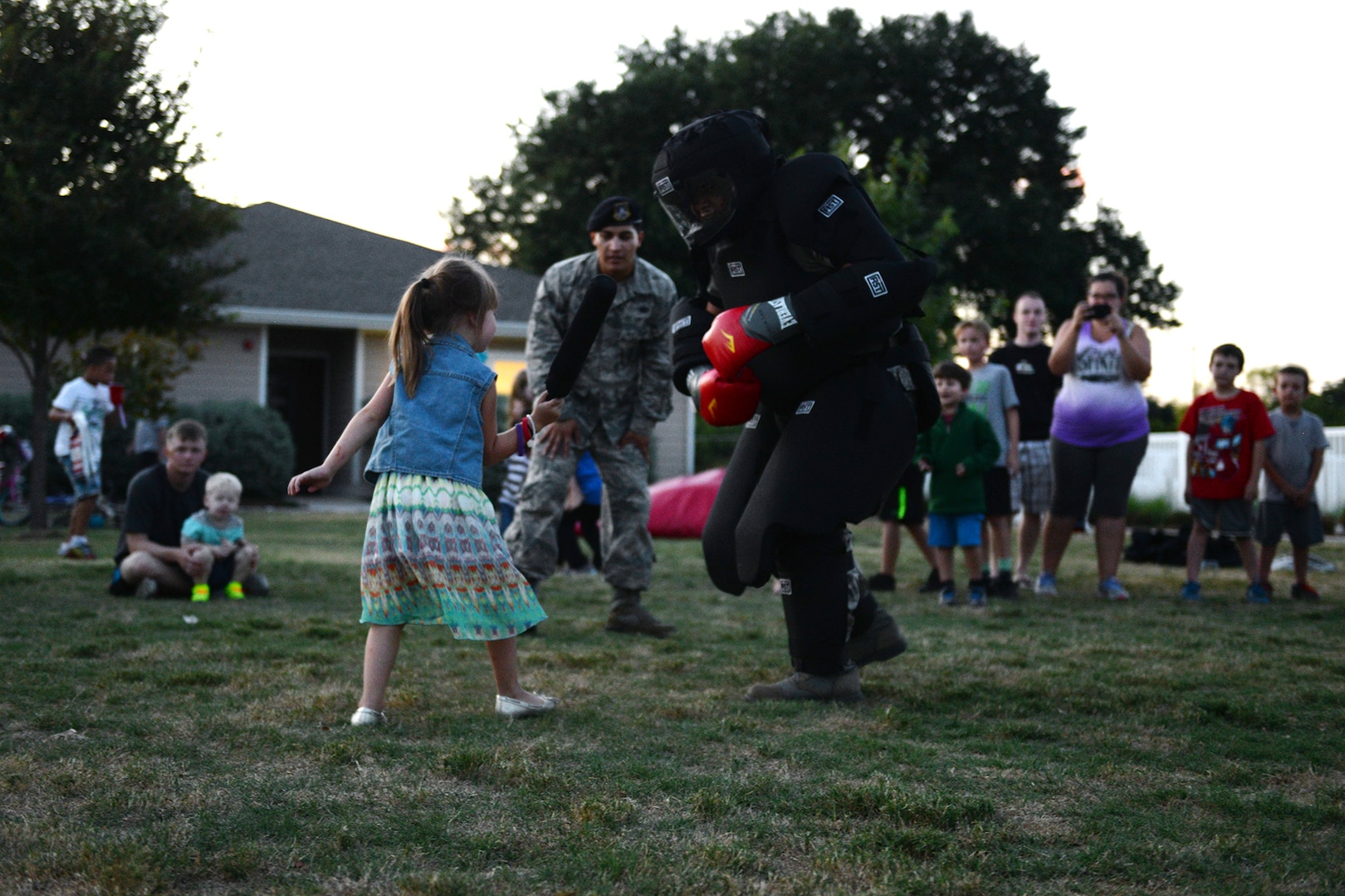 Senior Airman Taylor Williamson, 802nd Security Forces Squadron armory technician, speaks to children at examine the firearms displays, the Humvee, police cars and other police vehicles during National Night Out Oct. 6, 2015, at Joint Base San Antonio-Lackland, Texas. At the annual event there was also a bouncy castle, fire trucks, face painting station, a station that taught how to use a taser and a station that taught children scare away attackers with a baton. (U.S. Air Force photo by Senior Airman Krystal Wright/Released)