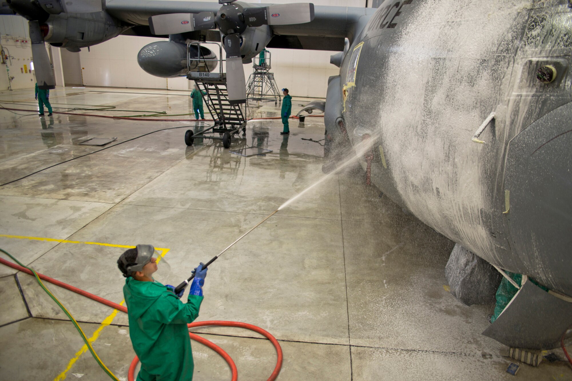 U.S. Air Force Senior Airman Christian Gonzalez, a crew chief assigned to the 50th Airlift Squadron, sprays soap onto a C-130H1 Hercules in a hangar at Little Rock Air Force Base, Ark., Sept. 14, 2015. Gonzalez is assisting in the preparation of the aircraft for what may be its final flight when it transits to Davis-Monthan Air Force Base, Ariz., where it will be stored for future use. (U.S. Air Force photo by Master Sgt. Jeff Walston/Released) 