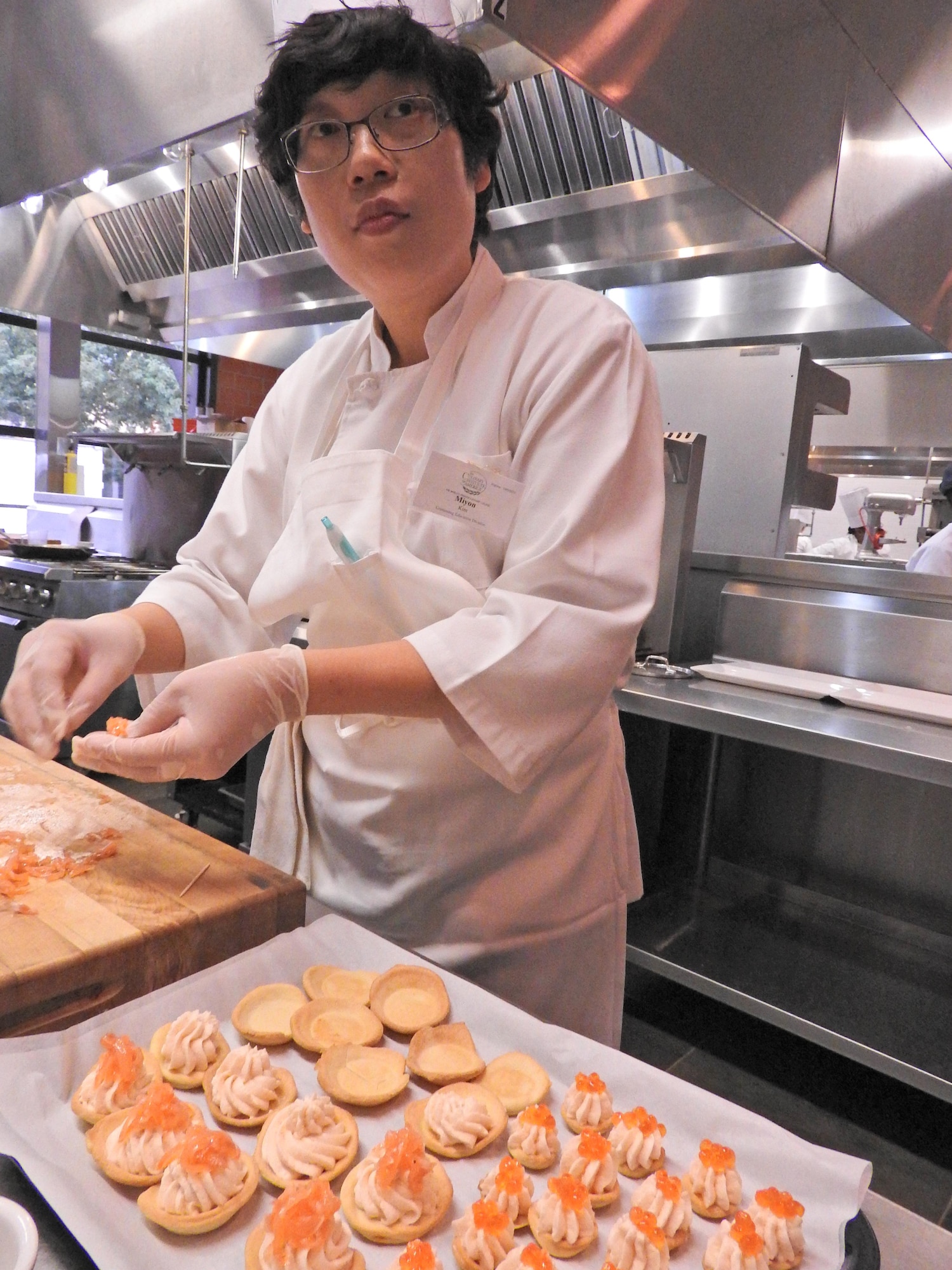 Miyon Kim, a cook from Kunsan Air Base, South Korea, awaits instruction from chefs leading the Advanced Culinary Skills course at the Culinary Institute of America’s San Antonio Campus. Kim is one of 12 Air Force food service personnel who attended the week-long course offered through a cooperative agreement between the Air Force Services Activity and the institute. (U.S. Air Force photo /Breanne Smith/Released)