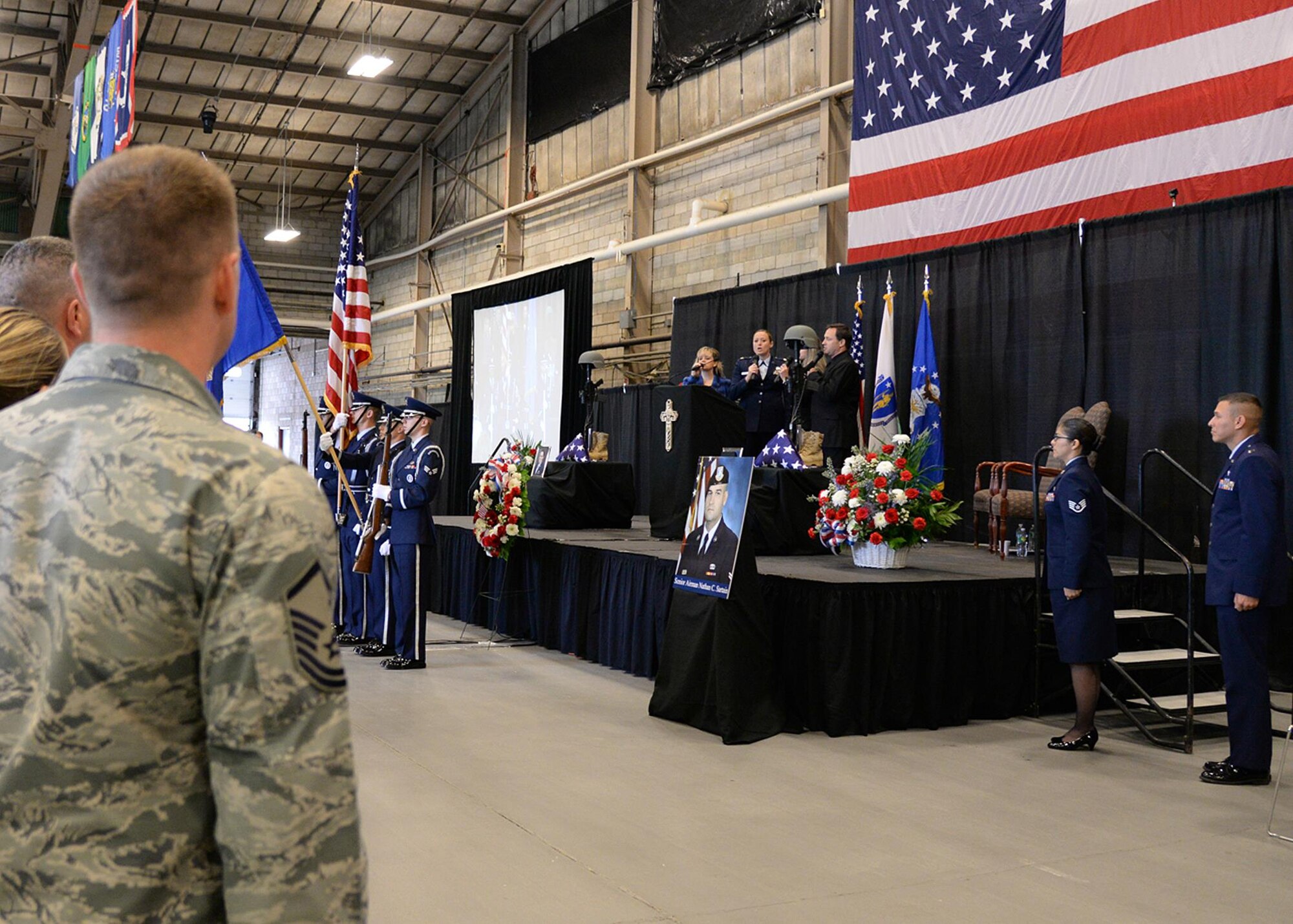 The Voices of Hanscom (from left) Michael Fields, Stacey Jones, Maj. Catherine Tobin and Andie Avram perform the National Anthem on stage during a memorial service at the Aero Club Hangar at Hanscom Air Force Base, Mass., Oct. 16. The service was held to honor Senior Airman Nathan Sartain and Senior Airman Kcey Ruiz, who were killed Oct. 2, when the C-130J Super Hercules they were on crashed shortly after takeoff from Jalalabad, Afghanistan. (U.S. Air Force photo/Jerry Saslav)