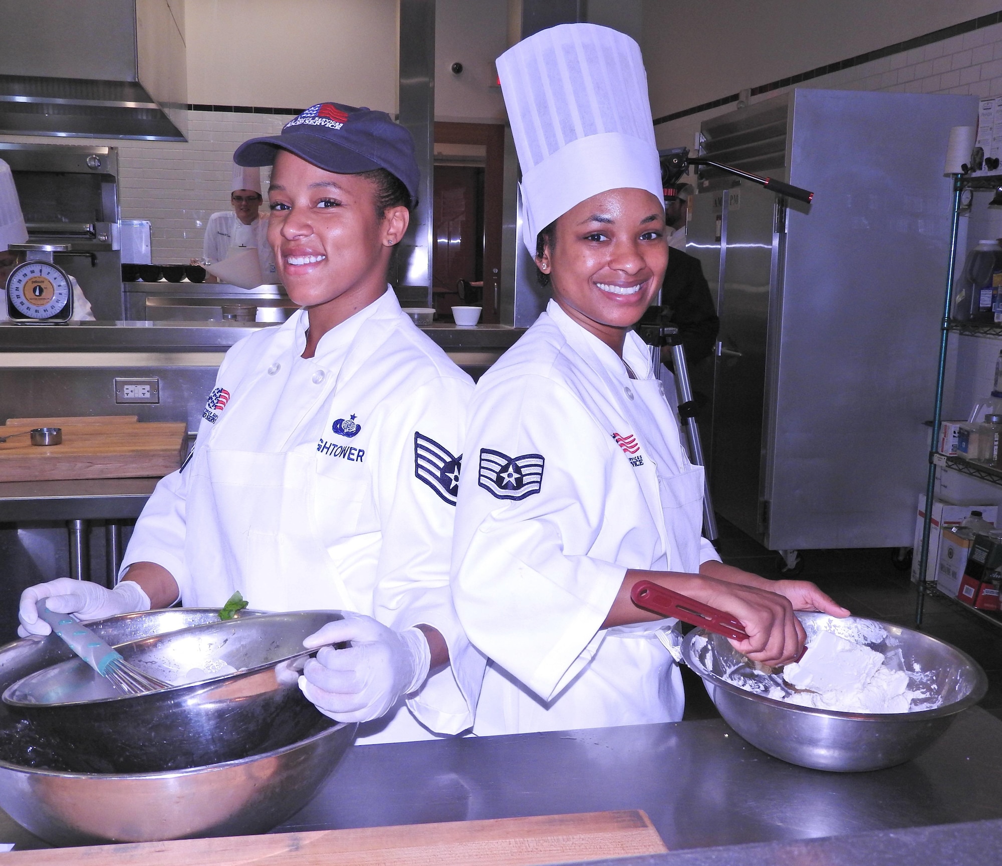 From left, Staff Sgts. Shantavis Hightower and Jacquelyne Ford take a quick break from cooking to pose for the camera. Hightower and Ford are part of a 12-person Air Force team from across the service that earned an Advanced Culinary Skills certification Oct. 9, from the Culinary Institute of America’s San Antonio campus. The week-long course is one of six offered through a cooperative agreement between the university and the Air Force. The program, which is managed by the Air Force Services Activity, gives active-duty Air Force and NAF employees the opportunity to hone their skills and learn new ways to improve business operations and efficiency in the kitchen. (U.S. Air Force photo/Breanne Smith/Released)
