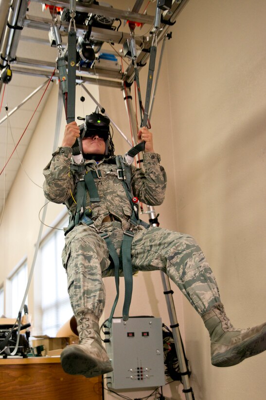 U.S. Air Force Senior Airman Casey Godwin, aircrew flight equipment apprentice, 913th Operations Support Squadron, pulls down on the risers of his parachute to correct a riser twist malfunction at Little Rock Air Force Base, Ark., Oct. 4, 2015. The simulator allows Airmen to learn from a virtual parachute jump, experiencing freefall, parachute openings and landings as well as many different malfunction scenarios in a safe environment. (U.S. Air Force photo by Master Sgt. Jeff Walston/Released)
